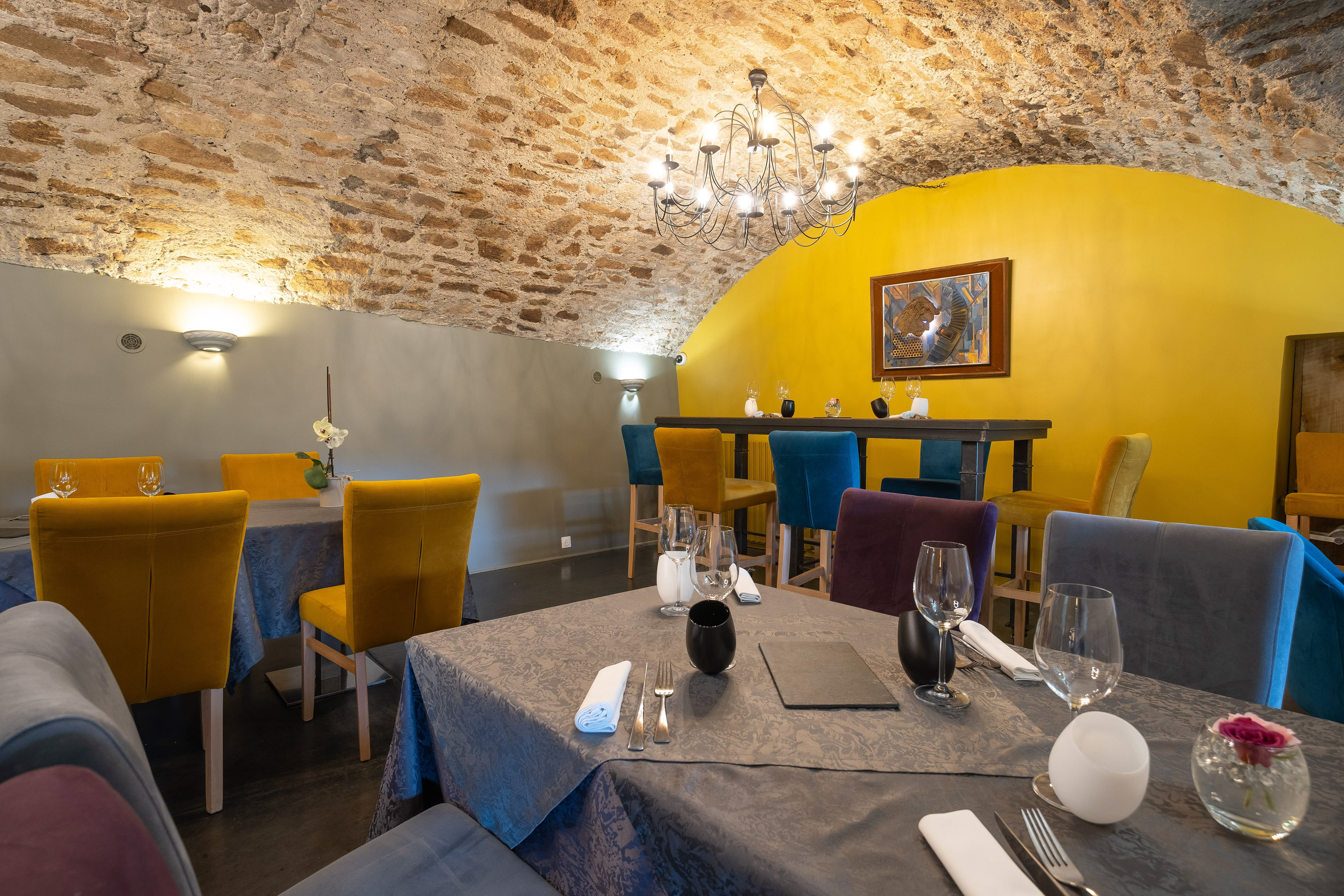 Salle de restaurant du Château en Saône-et-Loire, Bourgogne, avec un plafond voûté en pierre, des murs aux couleurs vives, et des tables élégamment dressées, créant une atmosphère chaleureuse et sophistiquée pour un repas raffiné.