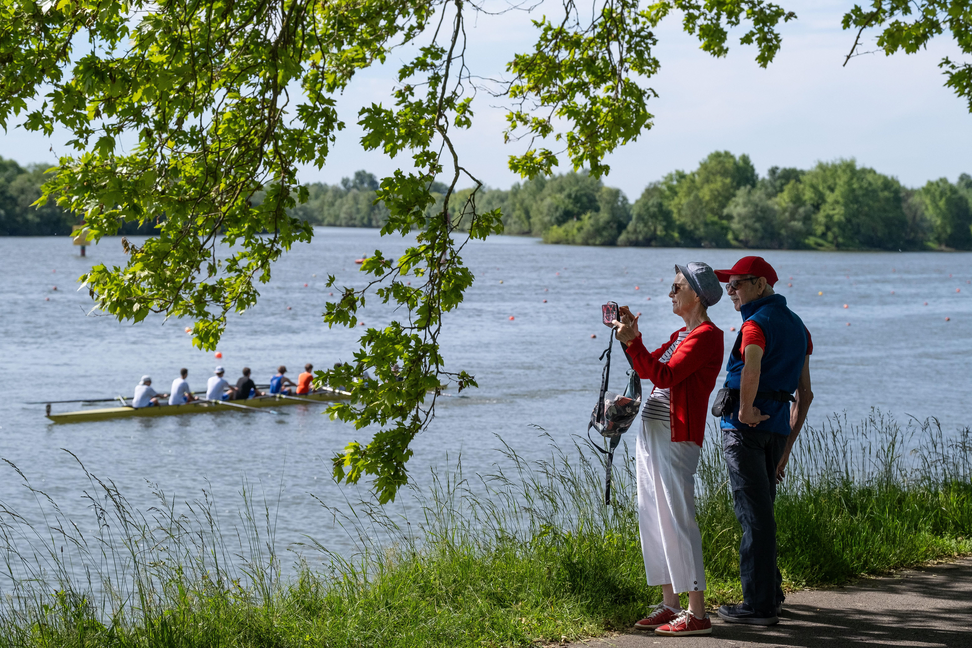 Spectateurs observant une compétition d'aviron au bord de la Saône à Mâcon, Saône-et-Loire, Bourgogne, Rhône-Alpes, capturant des souvenirs avec des appareils photo. Photographie capturée par Etienne Gatheron. Photographie institutionnelle.