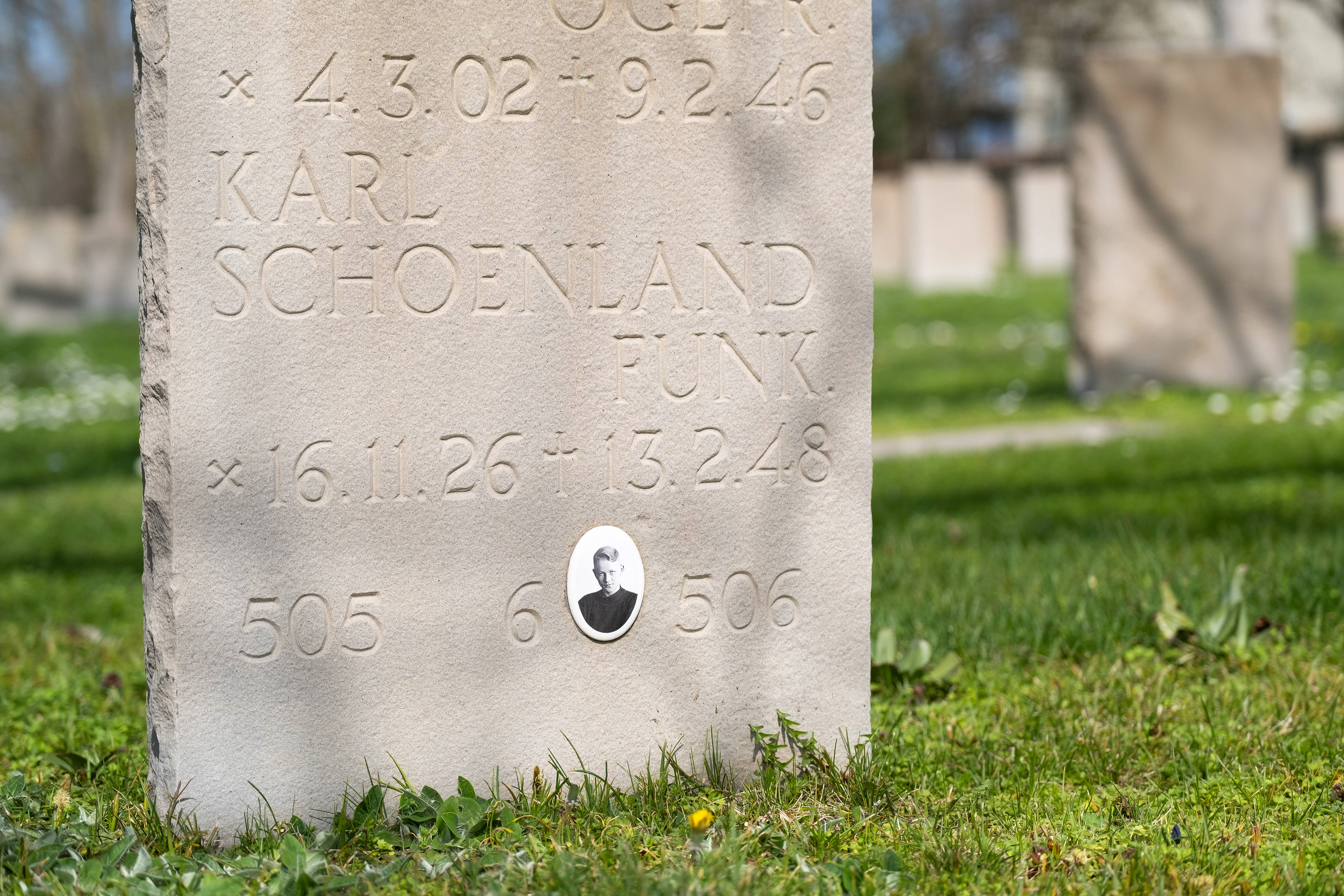 ierre tombale de Karl Schoenland au Cimetière Militaire Allemand de Dagneux près de Lyon, avec inscriptions gravées et photo du soldat. Importance historique et mémorielle. Photo par Etienne Gatheron, spécialiste des sites historiques, patrimoine culturel et tourisme mémoriel.