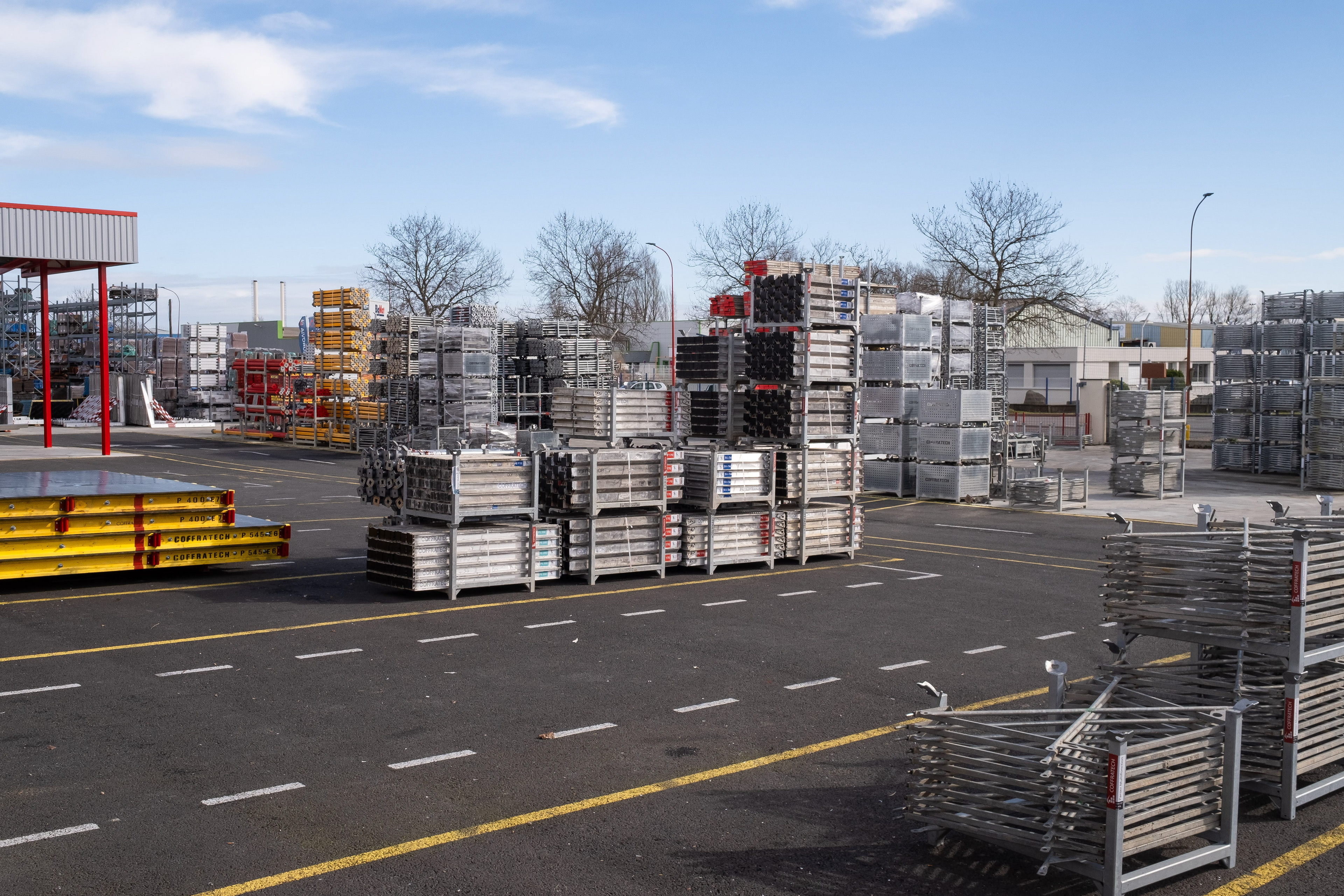 Zone de stockage en extérieur d'une entreprise industrielle à Mâcon en Saône-et-Loire, Bourgogne, Rhône-Alpes, avec des piles de matériaux et d'équipements divers sous un ciel bleu clair. Photographie capturée par Etienne Gatheron. Photographie institutionnelle.