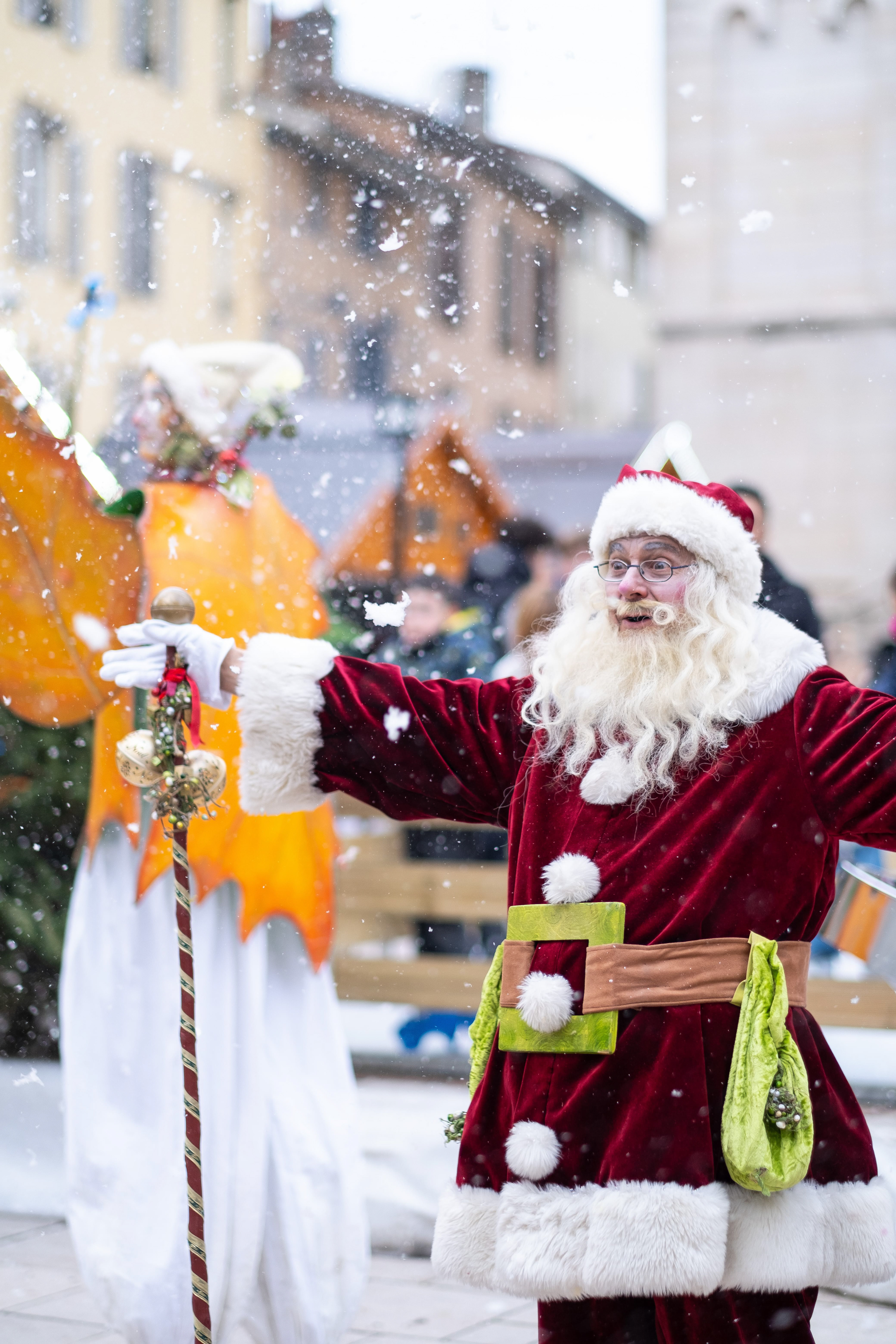 Père Noël accueillant joyeusement les enfants sous une légère neige artificielle lors d'une célébration à Mâcon, Saône-et-Loire, Bourgogne, Rhône-Alpes. Photographie capturée par Etienne Gatheron. Photographie institutionnelle.