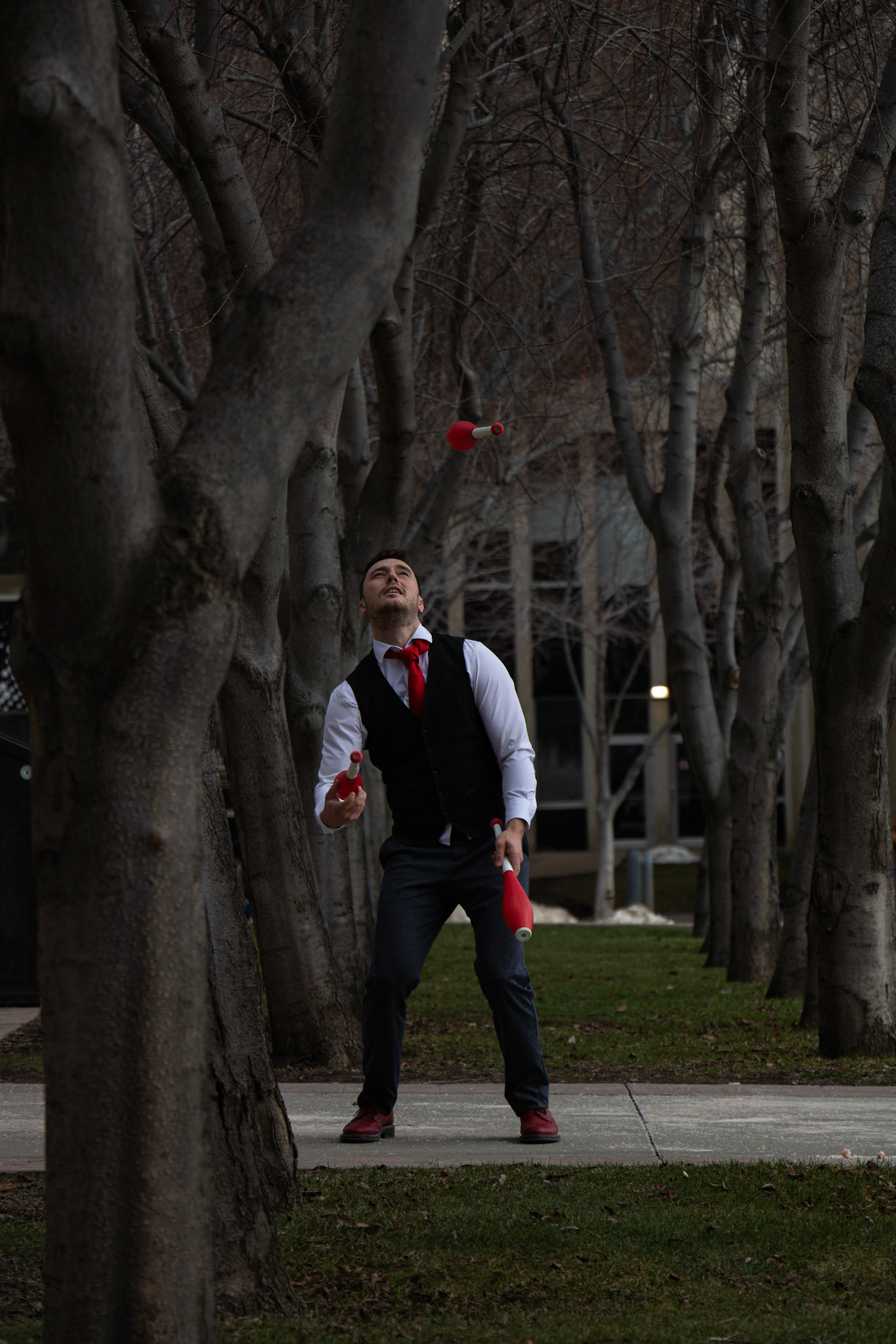 Jason Melnychuk, a renowned juggler, also known by his stage name JasonCircus, performs an entertaining performance while posing between trees, in front of the Heritage Hall in SAIT, Calgary on Wednesday, April 3, 2024. This event presented an excellent photographing opportunity for aspiring SAIT journalism students. Melnychuk, a seasoned entertainer since age 16, recently returned from shows in Australia.  (Photo by Armaan Khanna/The Press)