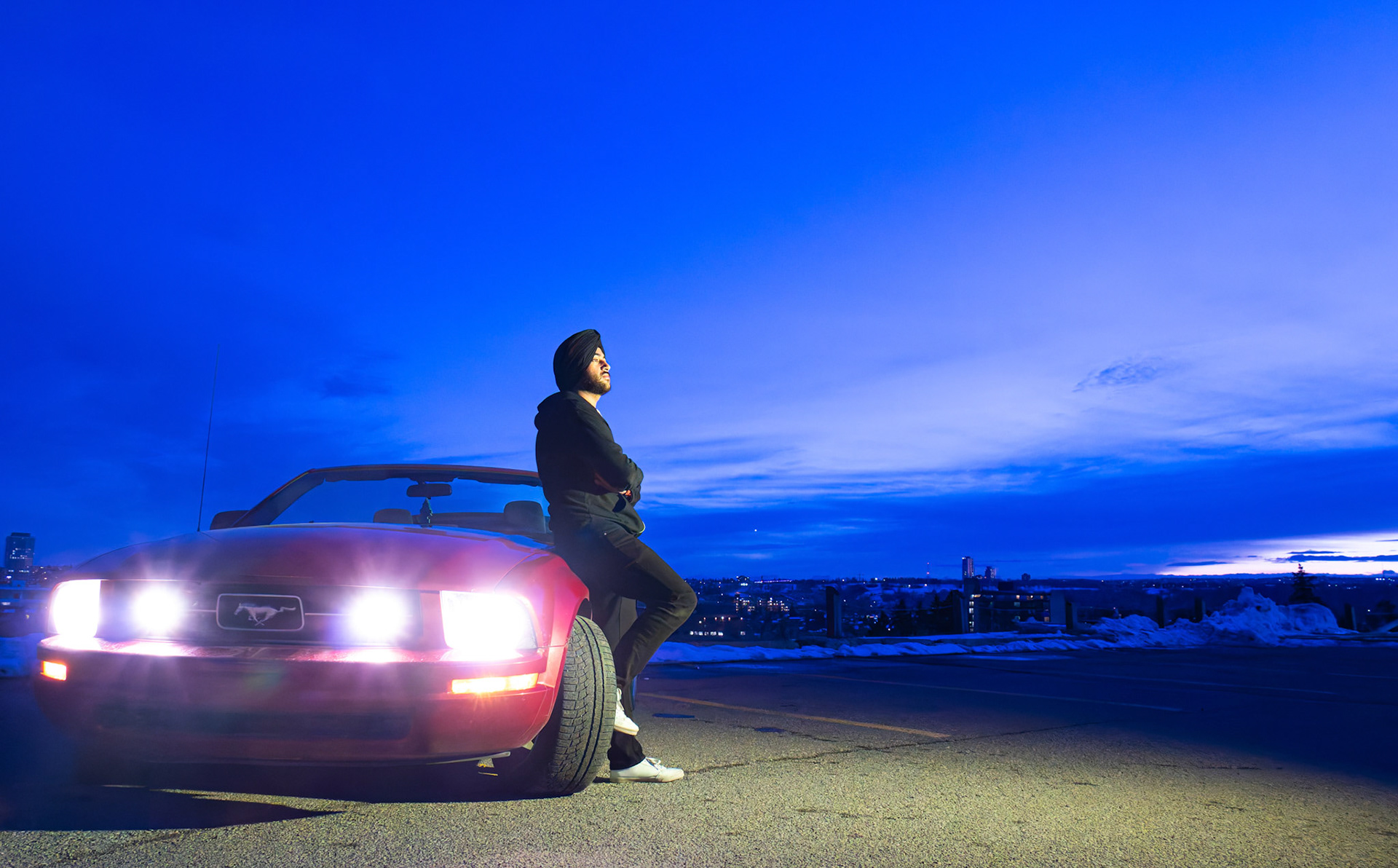 Harmandeep Singh Rathore, a full-time ITS student at SAIT, poses for a portrait with his Mustang in the SAIT parking lot, NW Calgary on Sunday, March 31, 2024. He is fond of classic and sports cars and dreams to own a Lamborghini Urus one day and make his parents proud by being a successful entrepreneur in the future. (Photo by Armaan Khanna/SAIT)