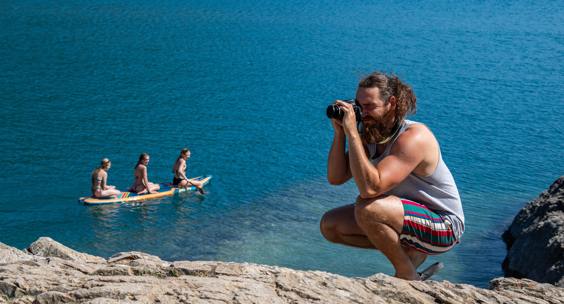 Brandon Nolan taking a photo, Sydney H. and Ella TK., Autumn Dai (right to left) kayaking in the background at Lake Minnewanka on Tuesday (July 9). ARMAAN KHANNA RMO PHOTO