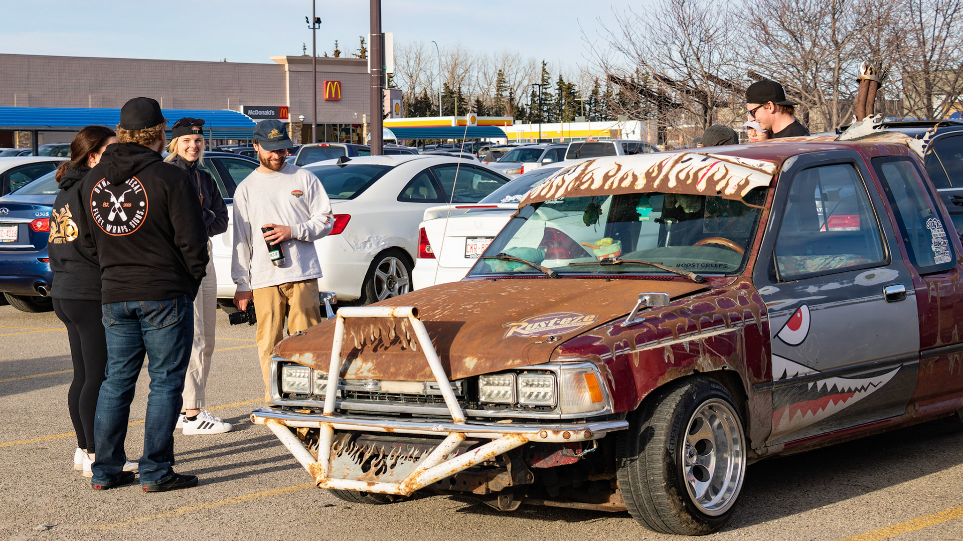 People gather to admire a modified 1999 Toyota pickup truck, owned by Luciana, at an unofficial car meet-up in the Royal Oak Shopping Centre parking lot in NW Calgary on Sunday, April 14, 2024. The lot filled up with a variety of modified vehicles displayed by car enthusiasts. The fun ended at sunset when the police showed up. (Photo by Armaan Khanna/The Press)