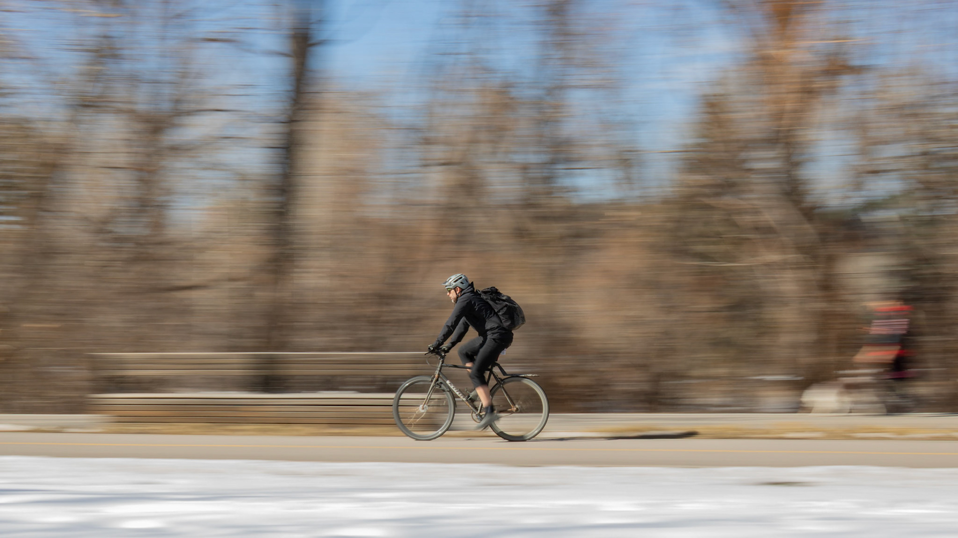 Cyclists pedal across a pathway near the Bow River in Calgary on Monday, April 1, 2024. With the snow melting away and weather forecasts predicting warmer temperatures this week onwards, Calgarians can expect to see increased activity near the Bow River in the upcoming days, making it a popular destination for recreation. (Photo by Armaan Khanna/The Press)