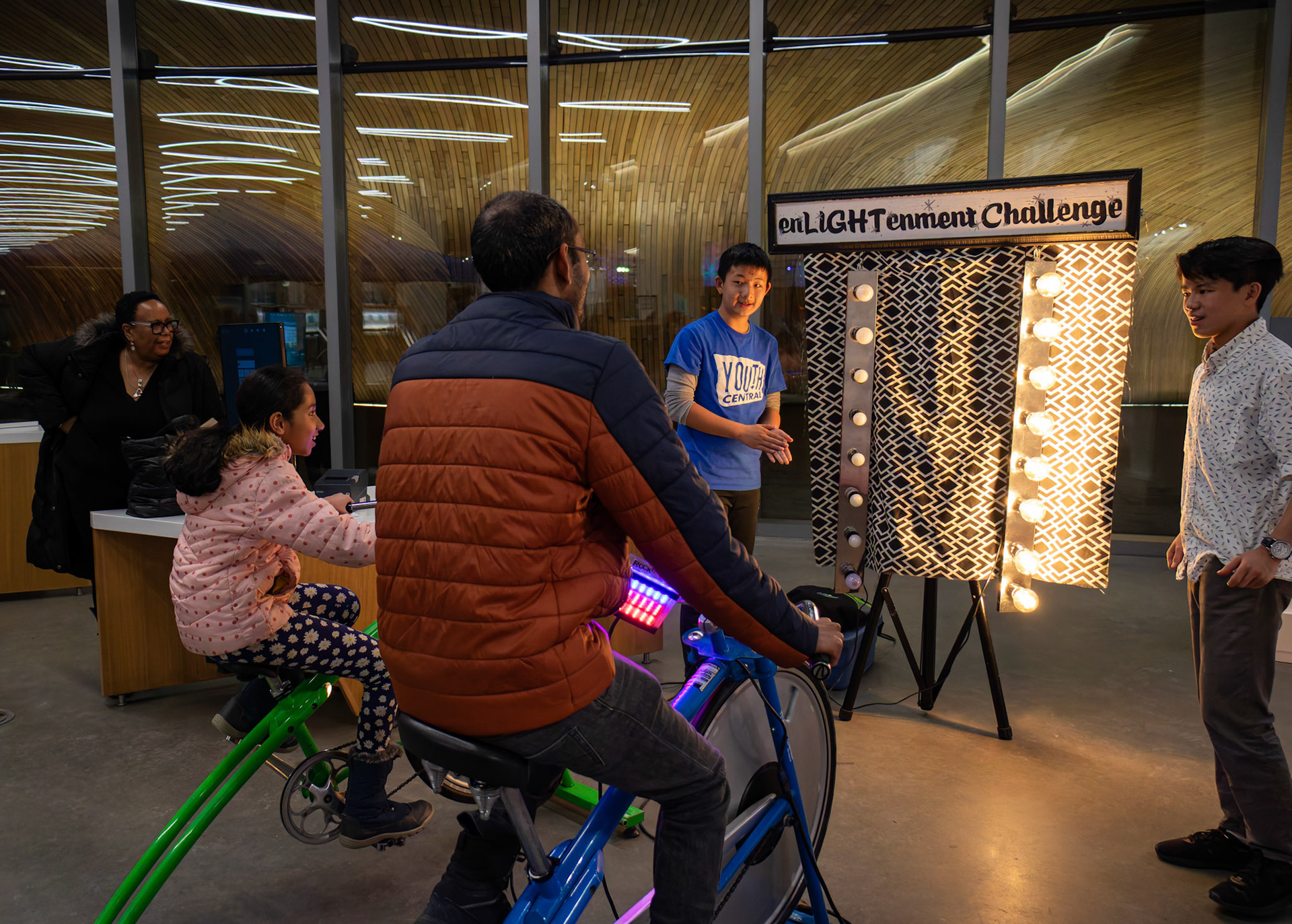 Suresh (right) and his daughter Jenna explore electricity generation by pedal power on specially designed bikes at the Earth Day event at Central Library in Calgary on Saturday, March 23, 2024. Calgary's "Unplugged Earth Hour" event offered residents a chance to celebrate sustainability in a lively atmosphere. Partnering with The City of Calgary, The Arusha Centre hosted the event, featuring music, entertainment, and interactive activities. They even encouraged Calgarians to extend their participation by turning off non-essential lights and electronics at home during Earth Hour.  (Photo by Armaan Khanna/The Press)