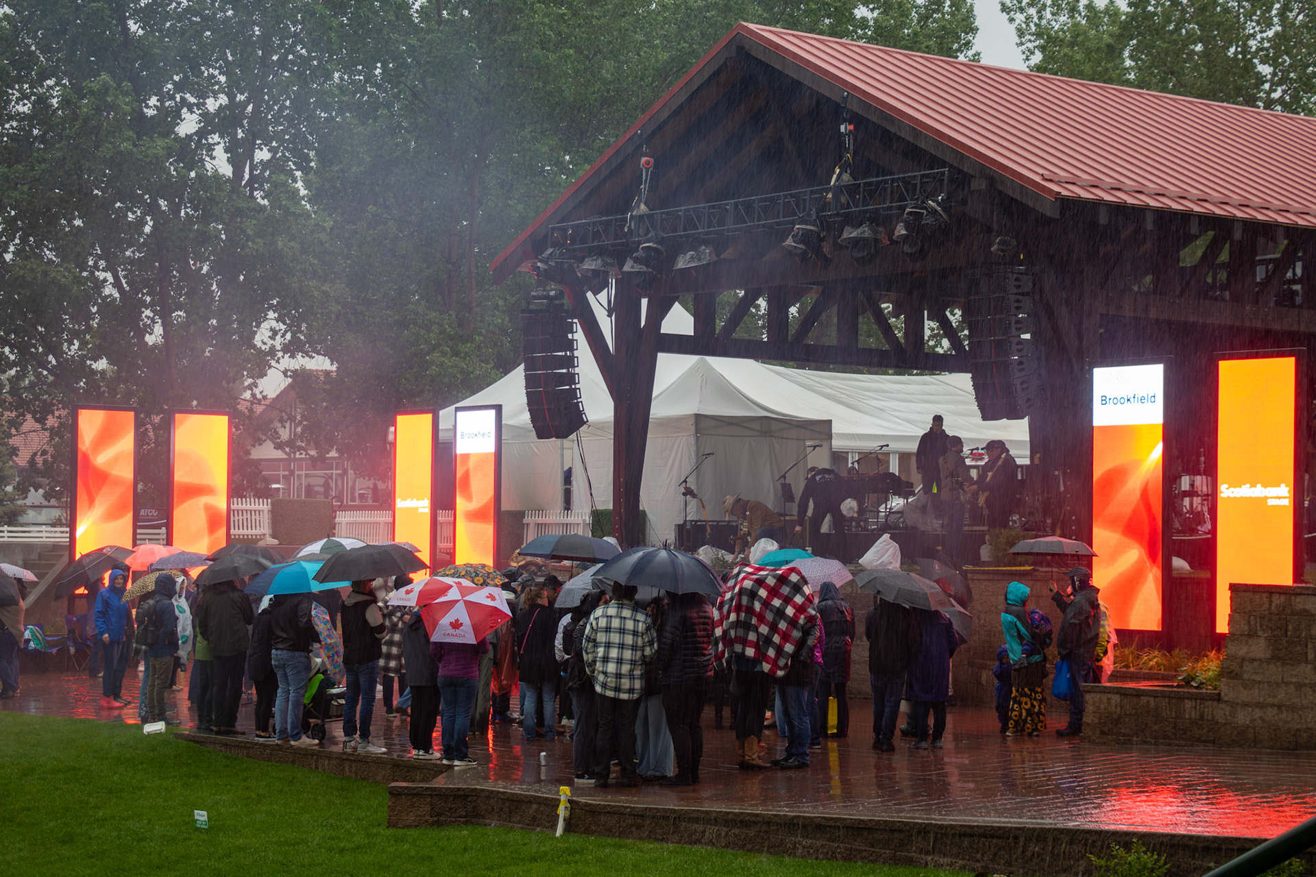 People enjoy a concert in the rain with umbrellas at Spruce Meadows, SW Calgary, on Saturday, June 15, 2024. Spruce Meadows is renowned for hosting top-tier equestrian competitions, such as the 'National' tournament, held from June 12 to 16, 2024. (Photo by Armaan Khanna/SAIT)