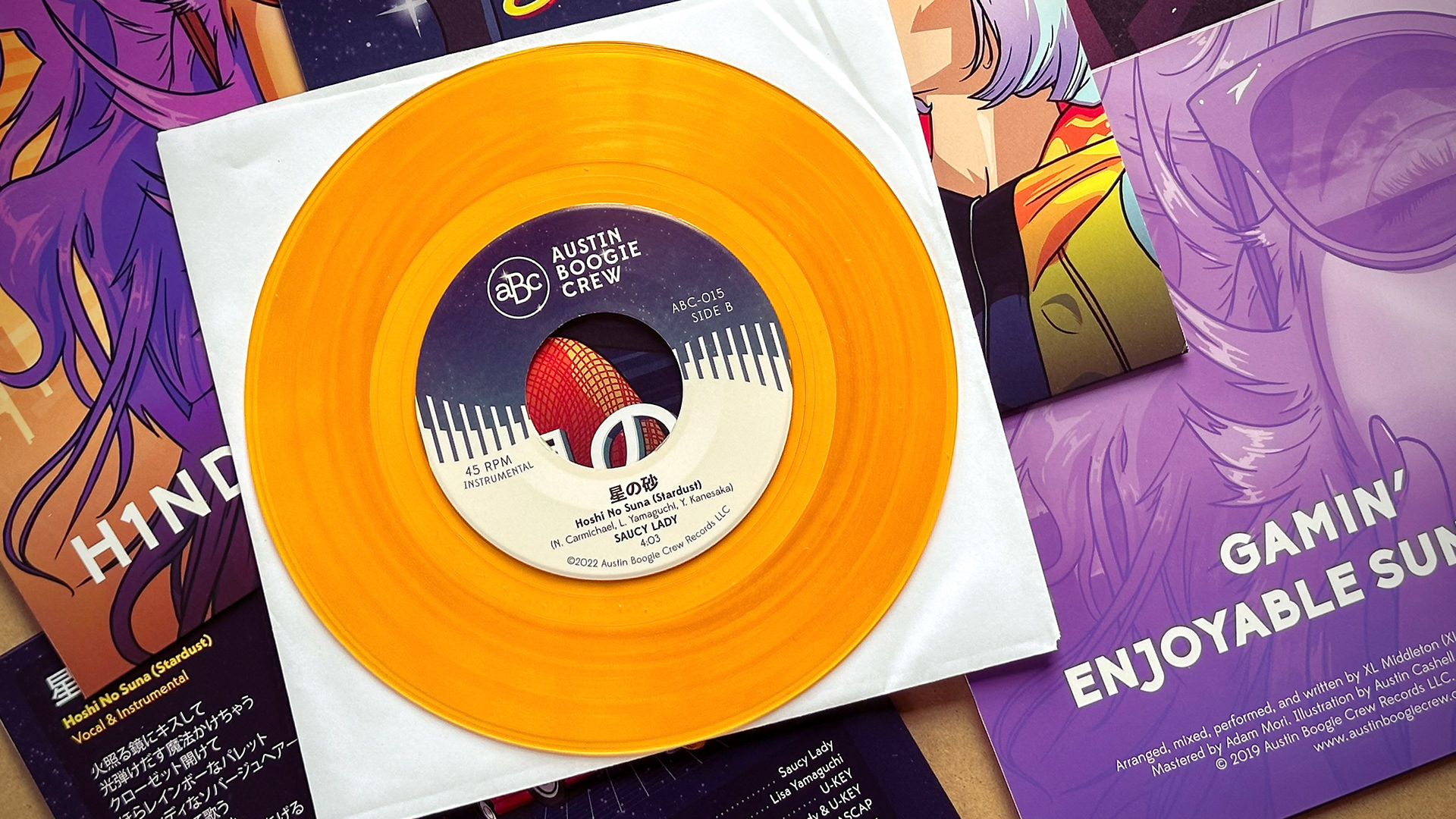 A translucent orange 7" vinyl record & packagind design details for the Saucy Lady, XL Middleton, and the Austin Boogie Crew record label