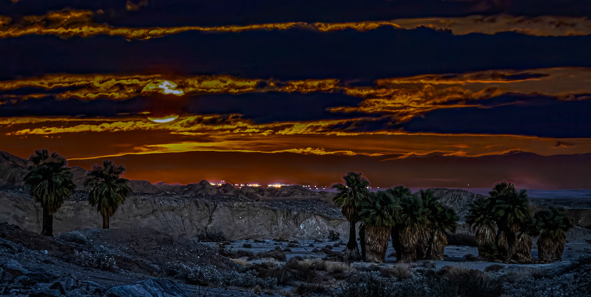 Oasis Moonrise: At the 17 Palms Oasis looking east towrds tthe Salton Sea.The palm grove in the foreground was photographed in the blue hour after sunset.  The moonrise in the background was photographed in twilight almost an hour after sunset.