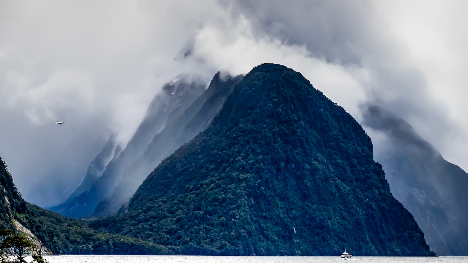 Mitre Peak, Milford Sound NZ: Cloud-shrouded Mitre Peak sits behind its smaller sister Footstool Mountain and is flanked on the left by Sinbad Gully,  a hanging valley.