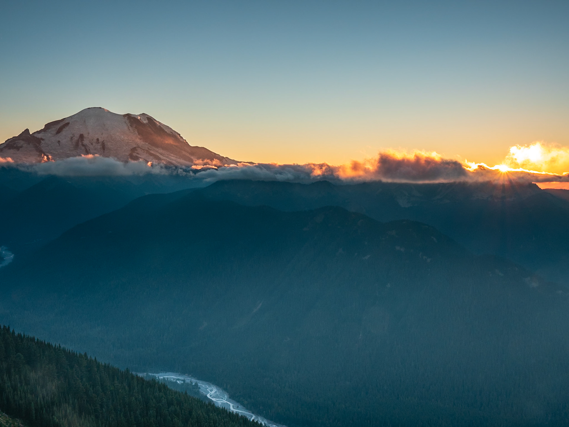 Mt. Rainier Sunset: Viewed from the top of Crystal Mountain, Mt. Rainier basks in a sunset filtered through low clouds.