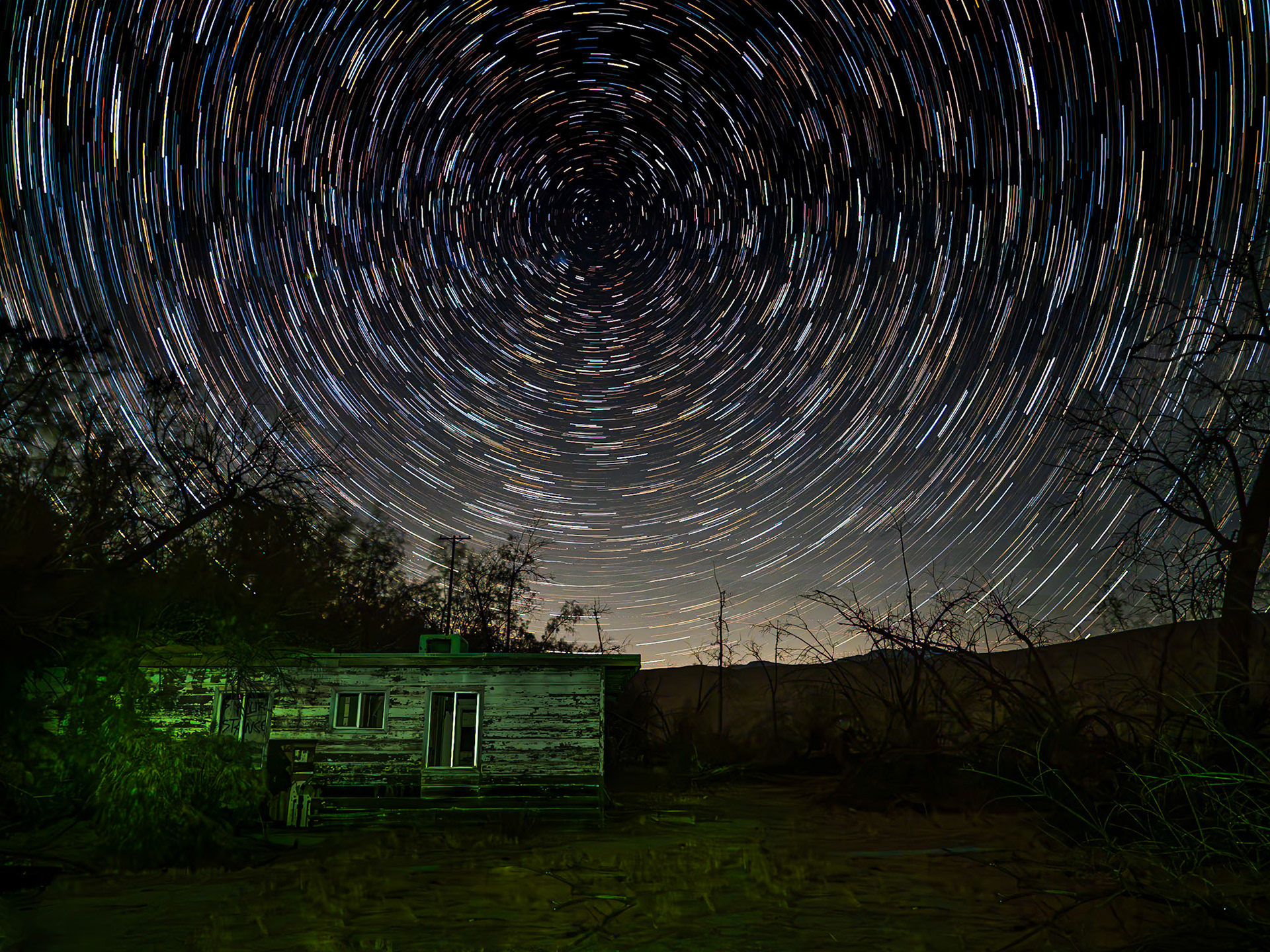 Abandoned Farmhouse: An abandoned house sits at the edge of  orange groves near the mouth of Coyote Canyon in the Anza Borrego Desert.  The star trails were captured with 120 15-sec images taken with an OM Systems OM-5 camera and composited in-camera to produce the final image.  The foreground exposure was supplemented with light painting while the camera was procuring the 120 individual images.