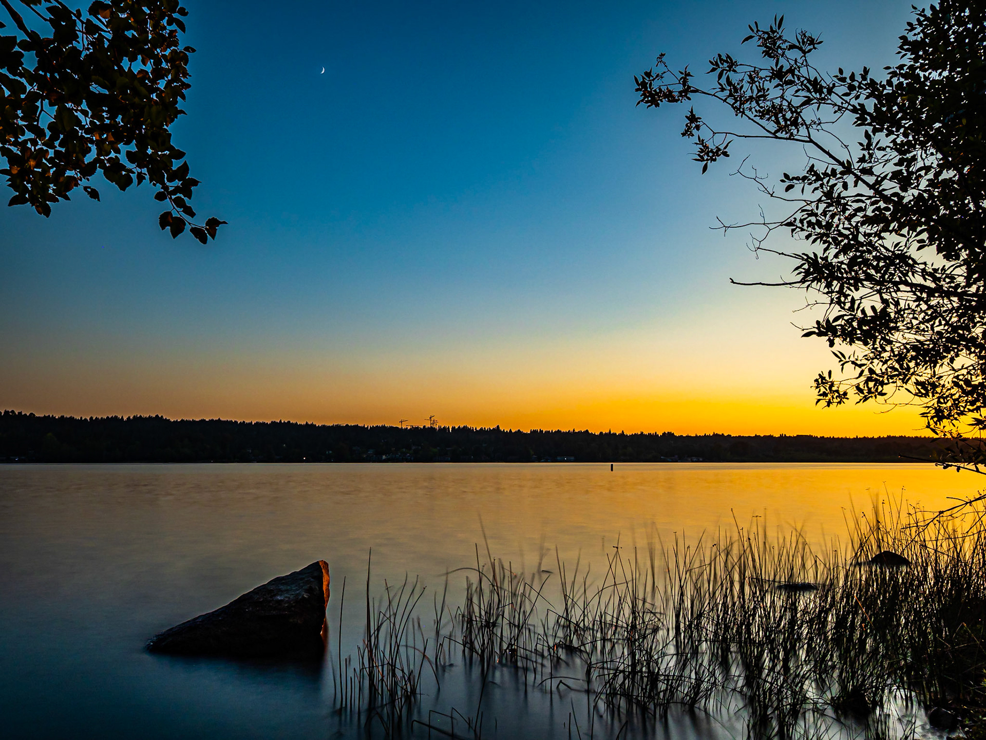 Blue Hour Crescent Moon: Crescent moon setting over Lake Sammamish in the blue hour after sunset.