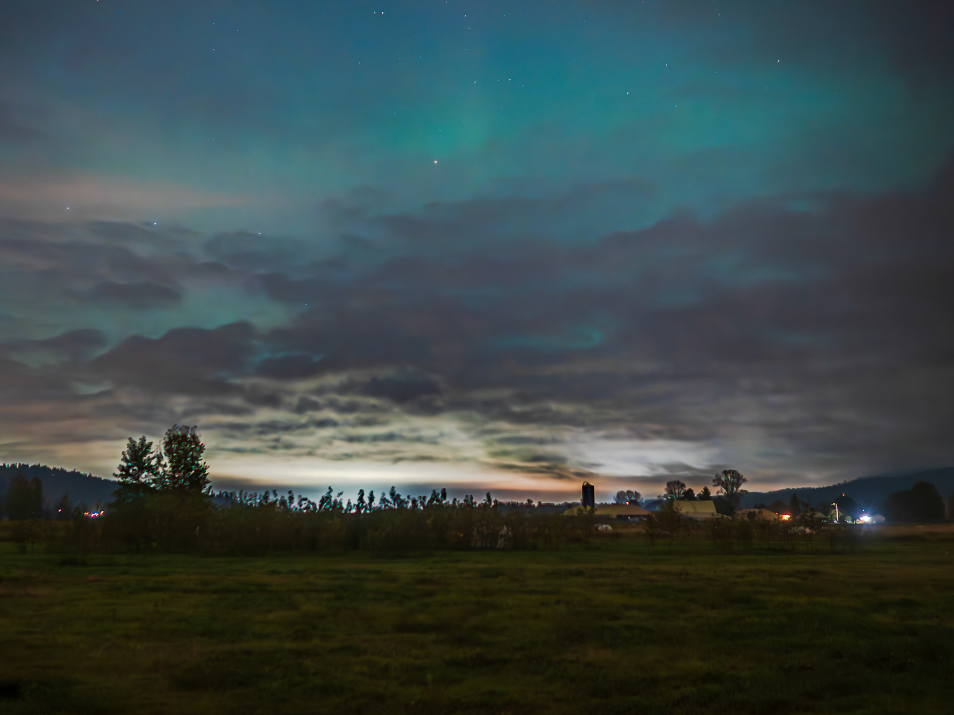 Northern Lights: Blue light of the aurora borealis and a few stars manage to glow through Pacific Northwest clouds near Duval Washinngton