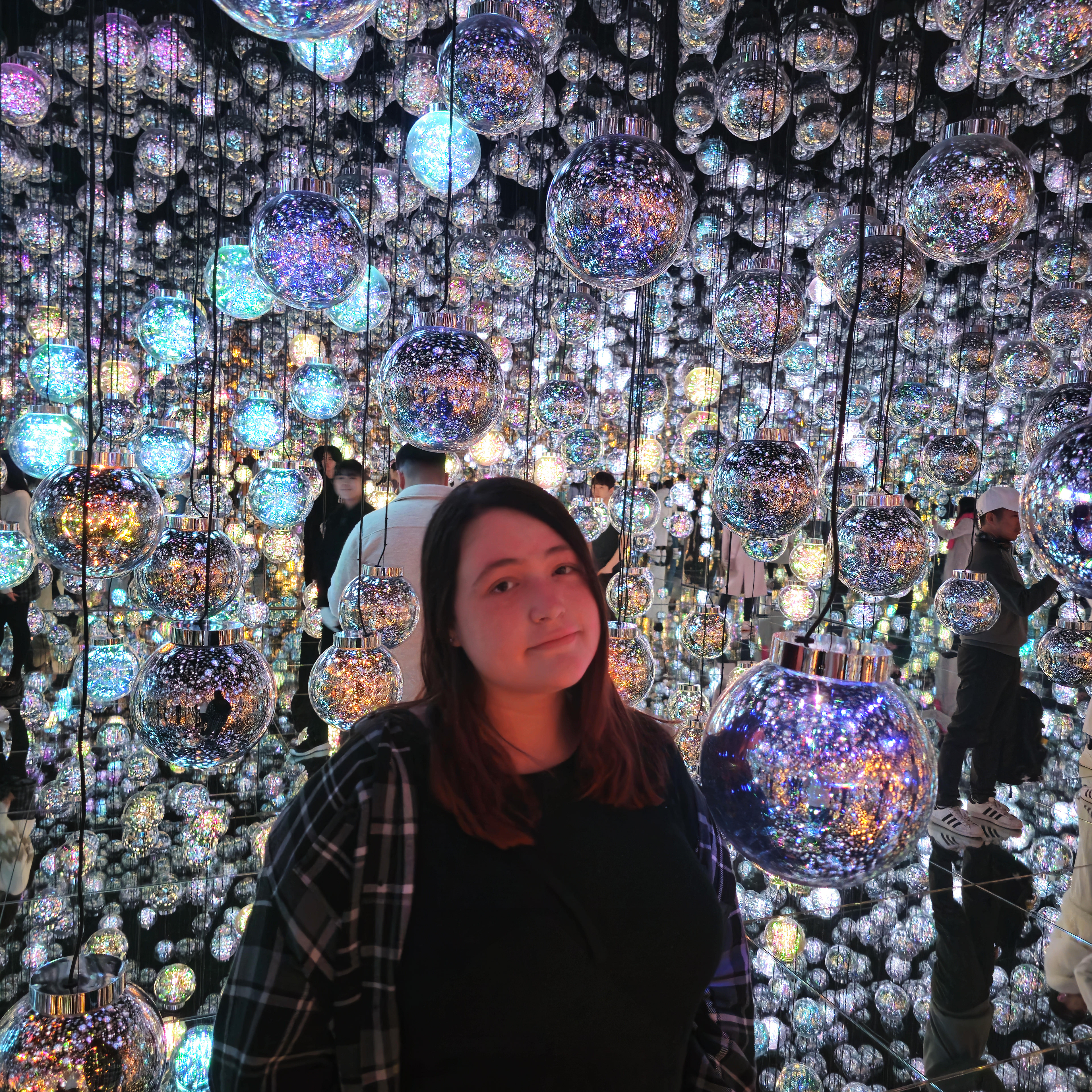Woman standing in a room surrounded by lights at TeamLab Borderless in Tokyo, Japan
