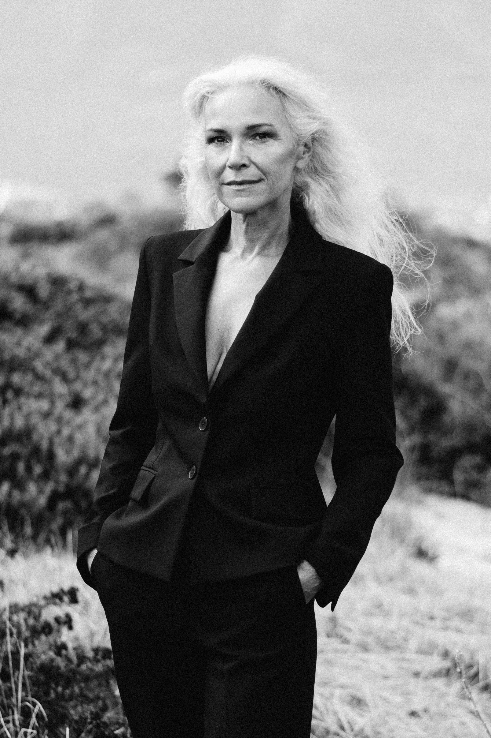 Black and white three-quarter portrait of mature woman in classic black suit, confident and poised, looking directly at camera, editorial and storytelling style, women’s outfit inspiration