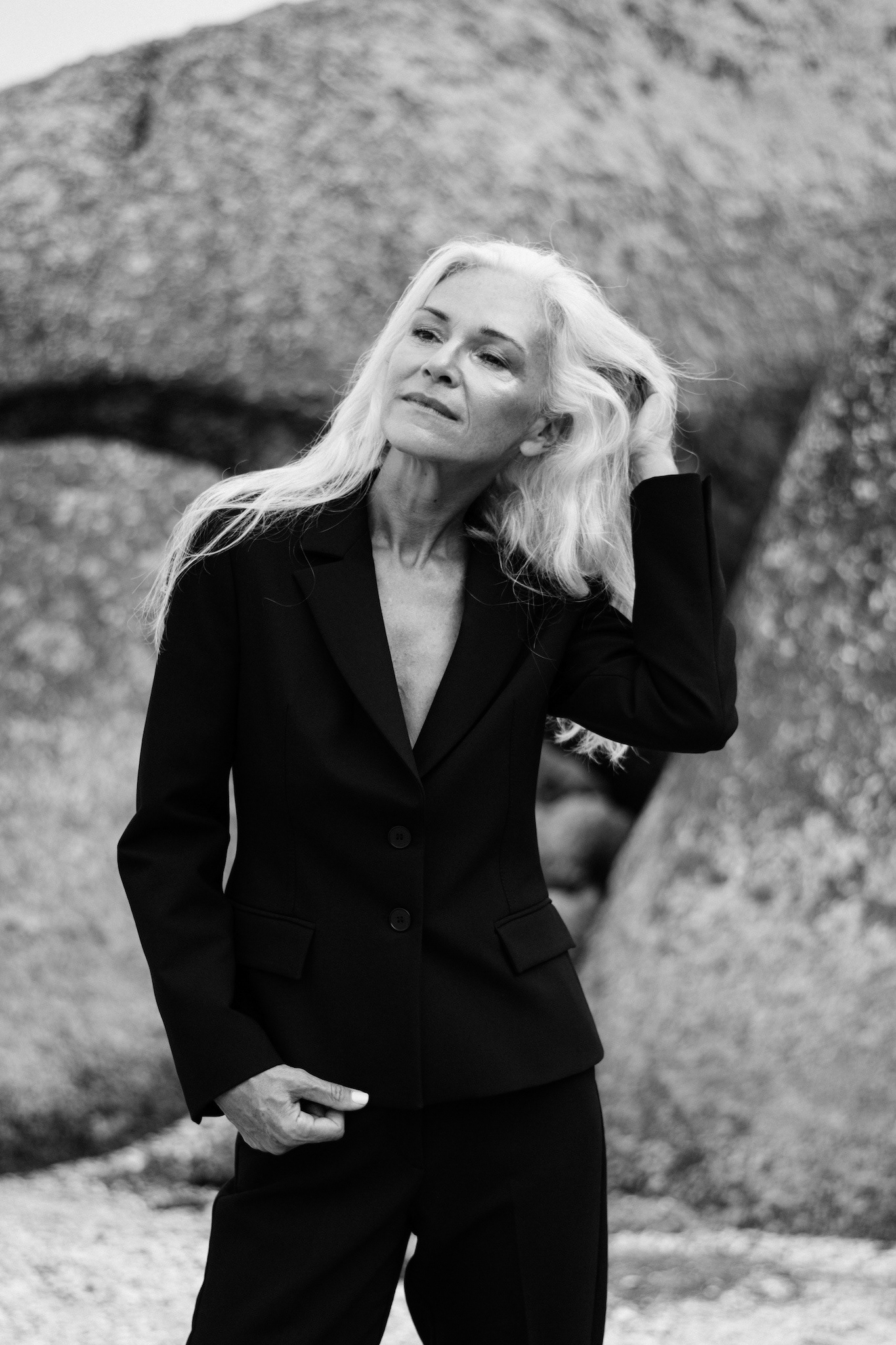 Three-quarter black and white storytelling portrait of a mature model on a Cape Town beach, hand in grey hair, looking away.