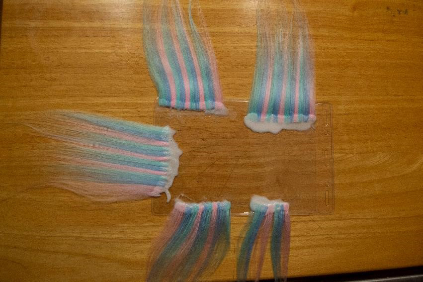Wefts of hair made out of colored yarn that has been brushed out.