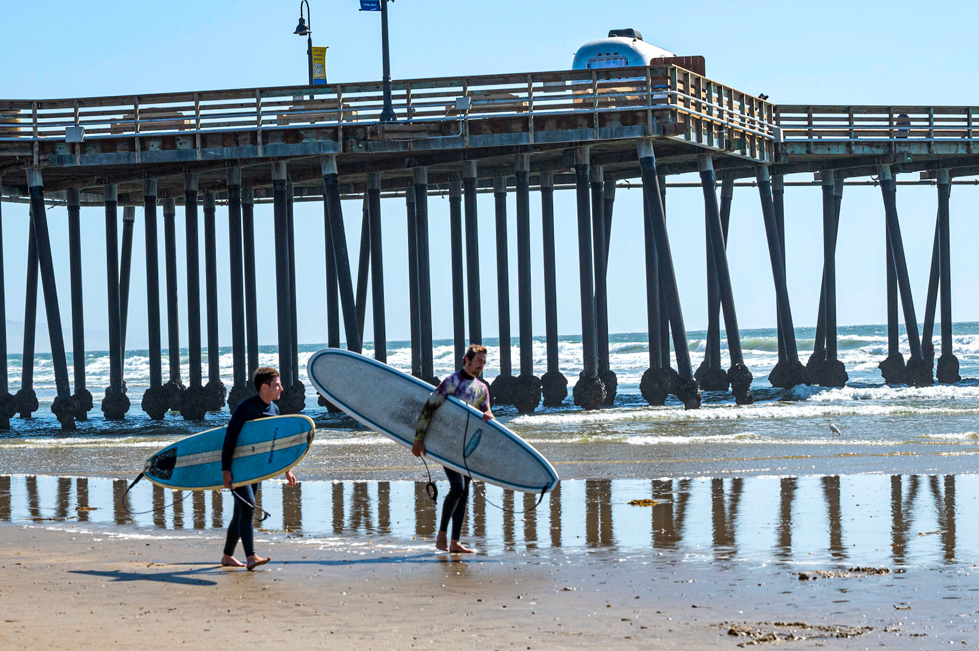 Surfers under the pier, Pismo Beach, California