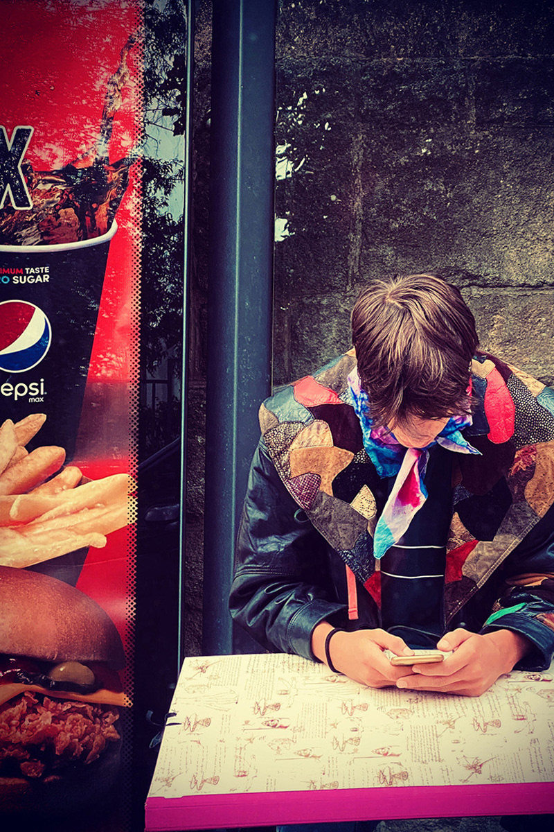 Individual artist waiting for bus close to mainstream poster