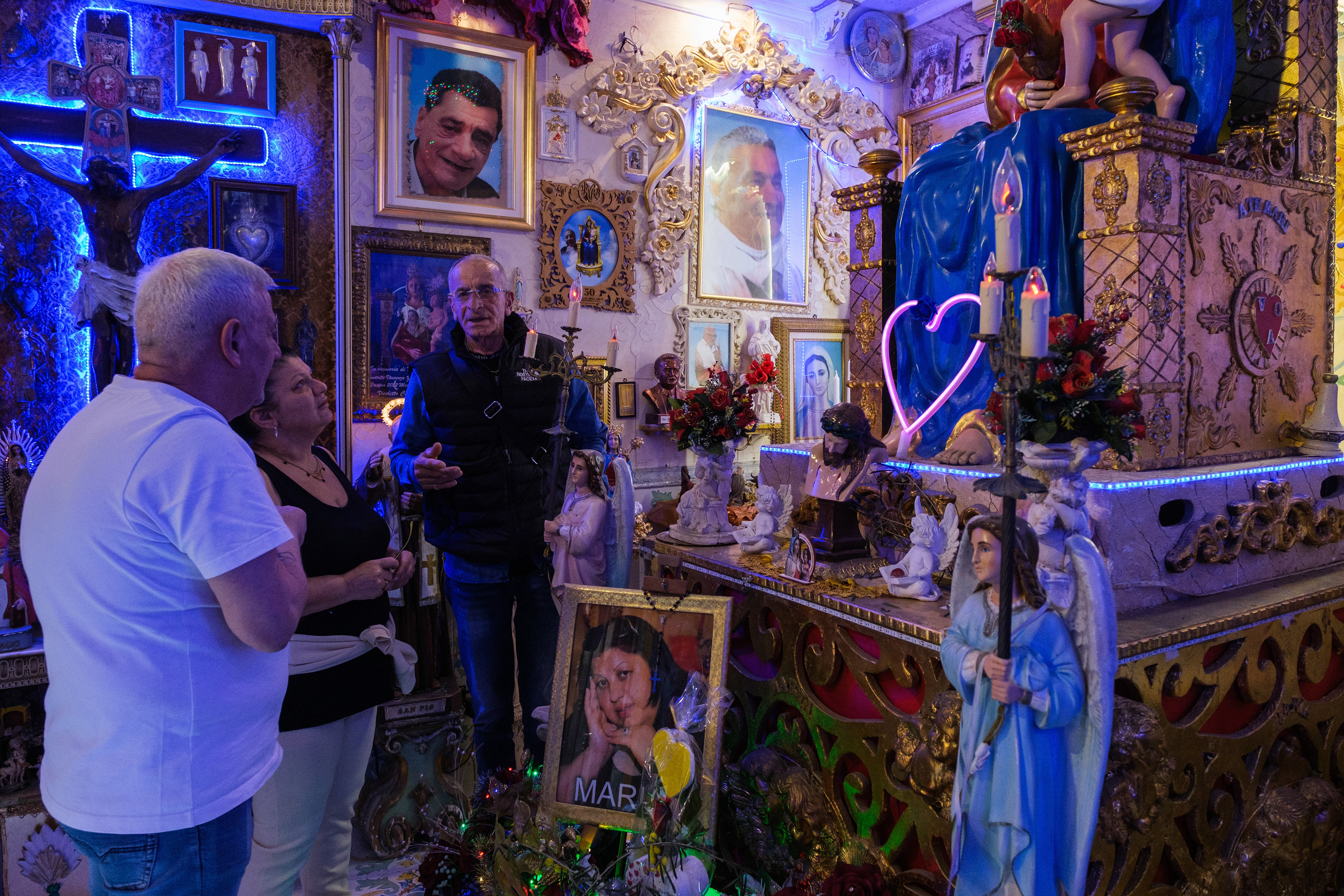 Naples (Italy): The interior of the community chapel in the Rione Sanità district, densely packed with framed photographs of various deceased locals. Started by Vincenzo for his wife Maria, the sanctuary expanded organically as neighbors added their own family portraits, banners, and votive offerings.