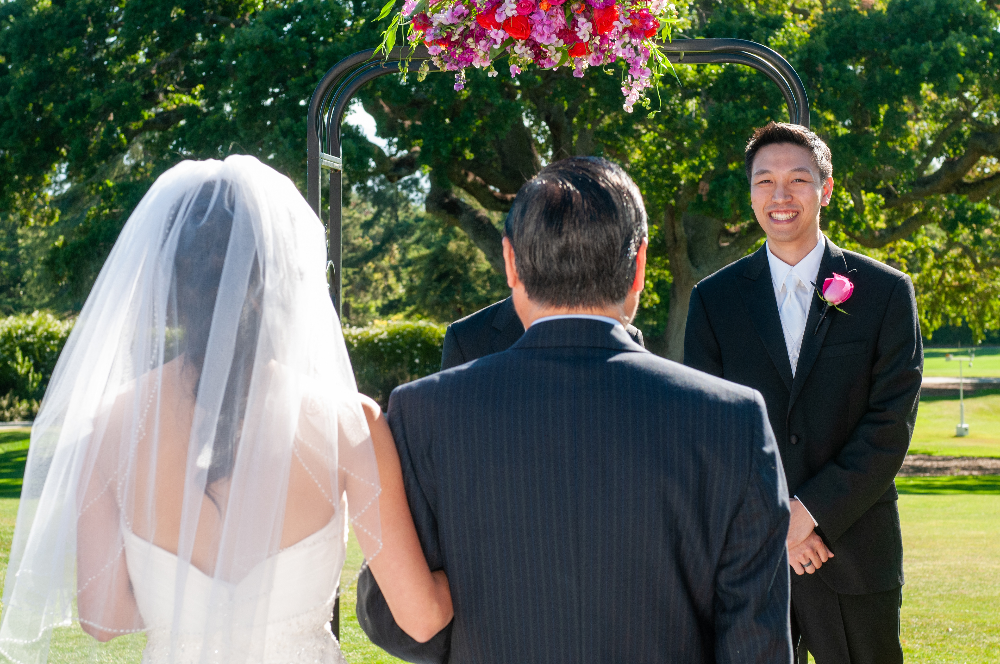 An elegant outdoor wedding ceremony on the greens at San Jose Country Club, with the groom watching as the bride walks down the aisle against sweeping Silicon Valley views.