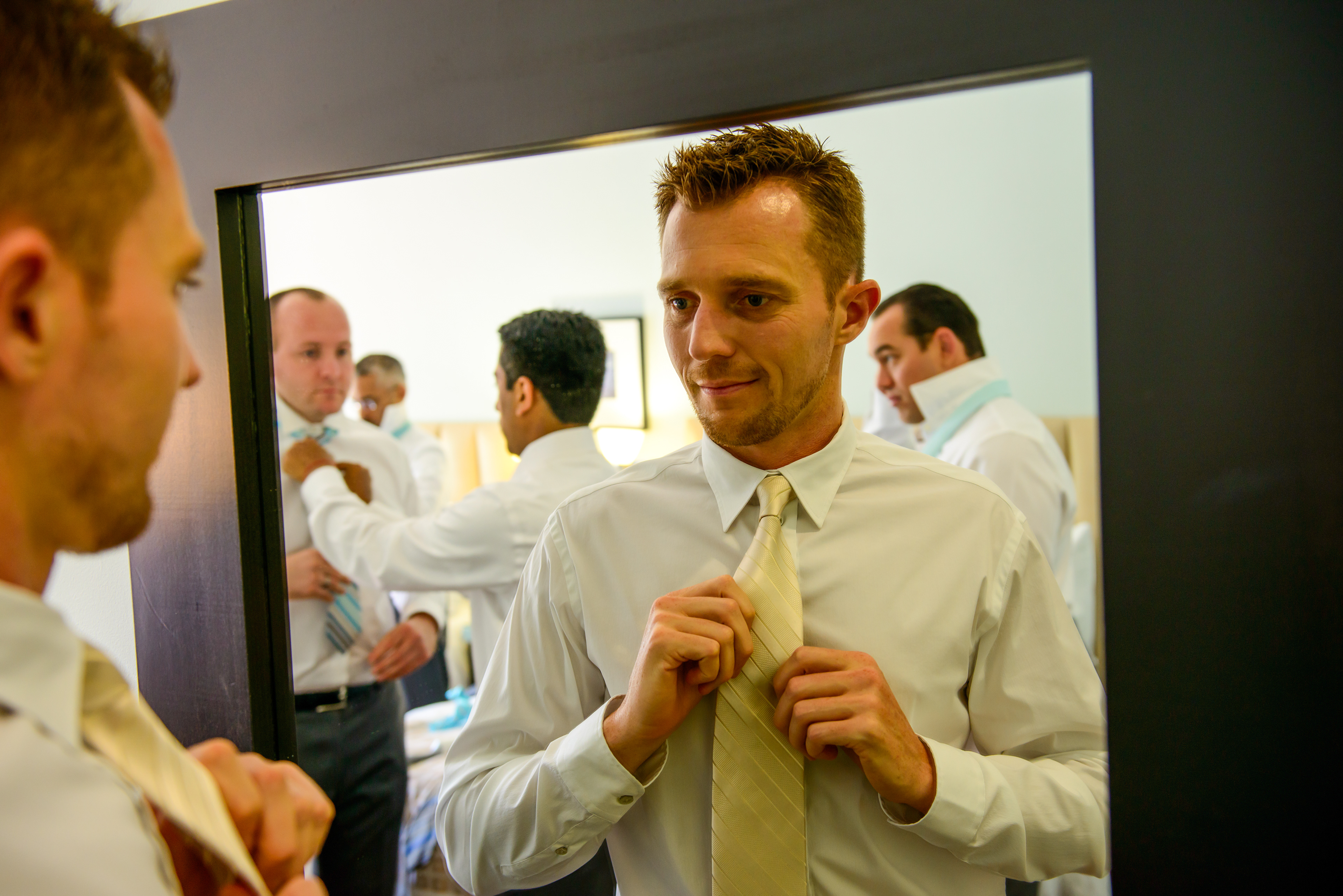 Groom adjusting cufflinks with champagne glass nearby