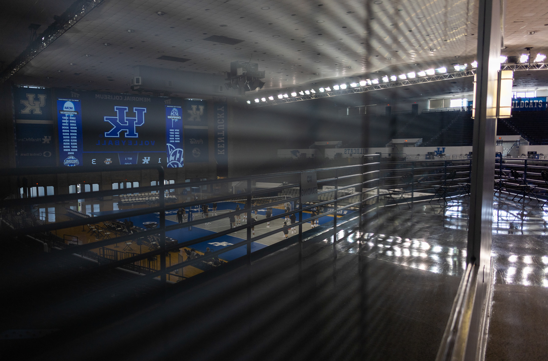 A reflection of the University of Kentucky office rooms shows the Ohio University Volleyball team warming up before the game.