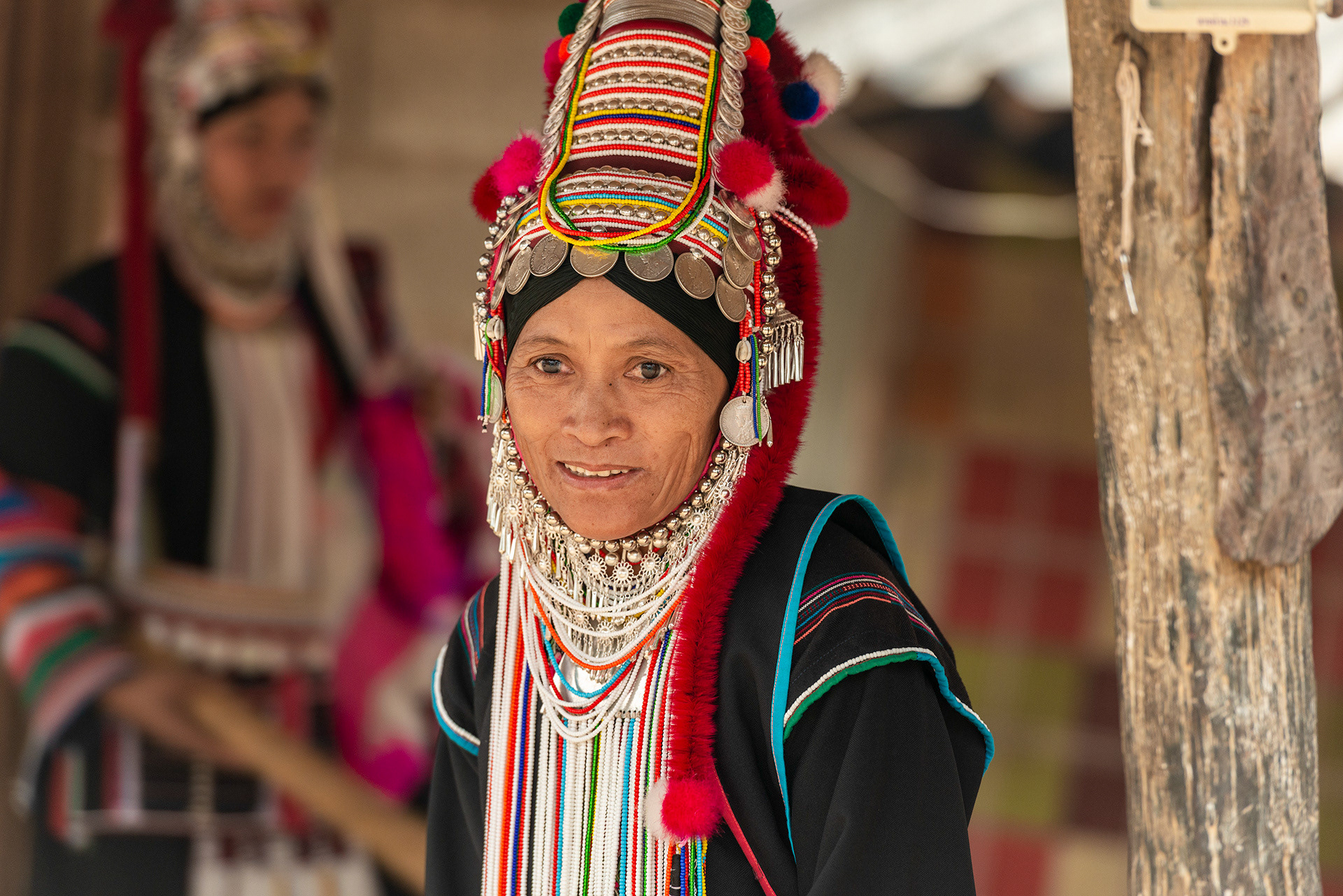 The back and the sleeves of the jacket are embellished with embroidery, satin stitches of bright colours, seeds, silver buttons, coins, beads, shells or tassels depending on the sub-group of Akha