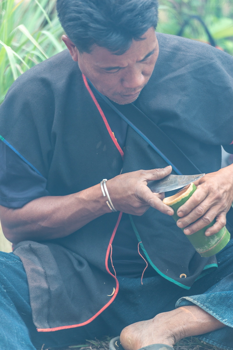 In the smoke of the open fire, Chermu prepares the cooking and drinking vessels from bamboo