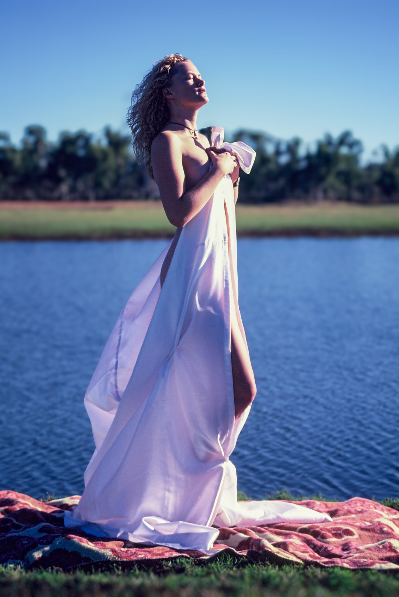 young lady in draped in white at lake edge