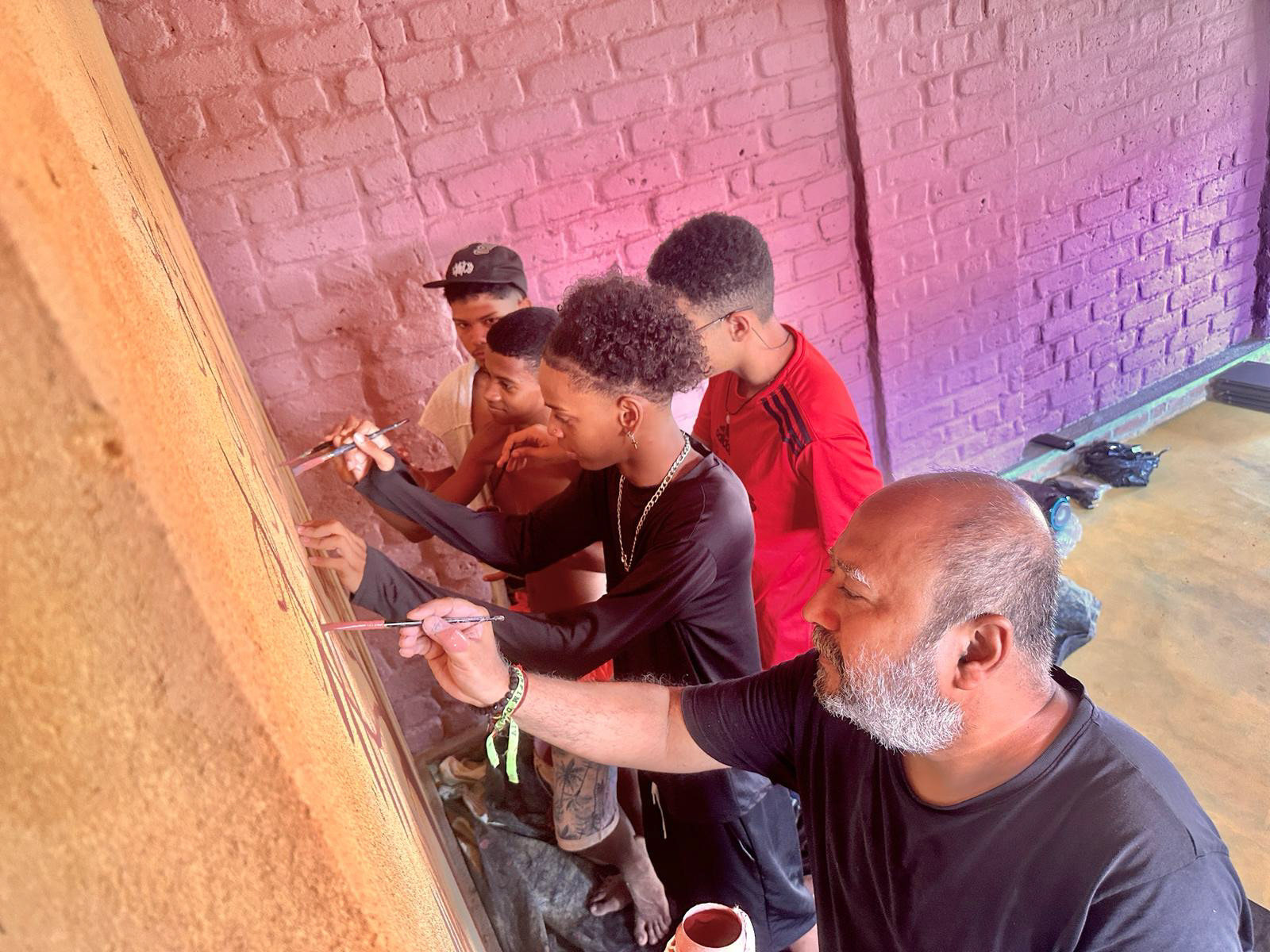 Kaushik, artista indiano, junto com jovens, na pintura da coletiva com tinta de terra.