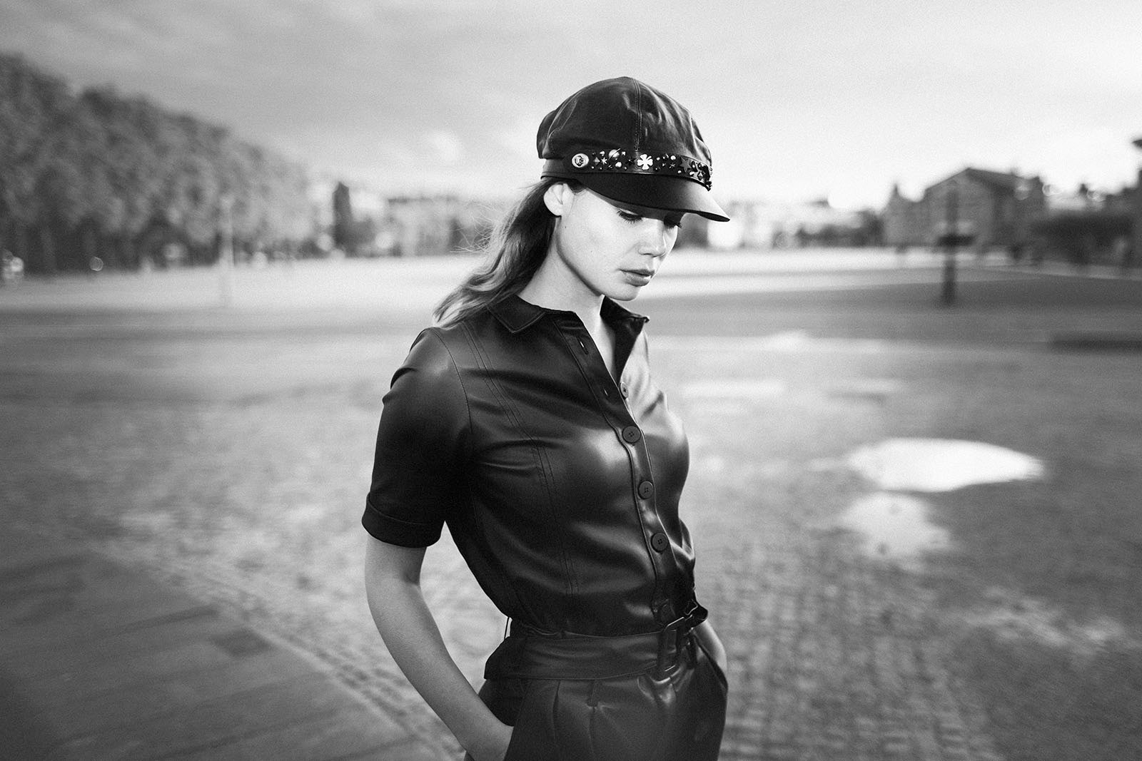 Zwartwit foto van model in zwart leer latex met pet op