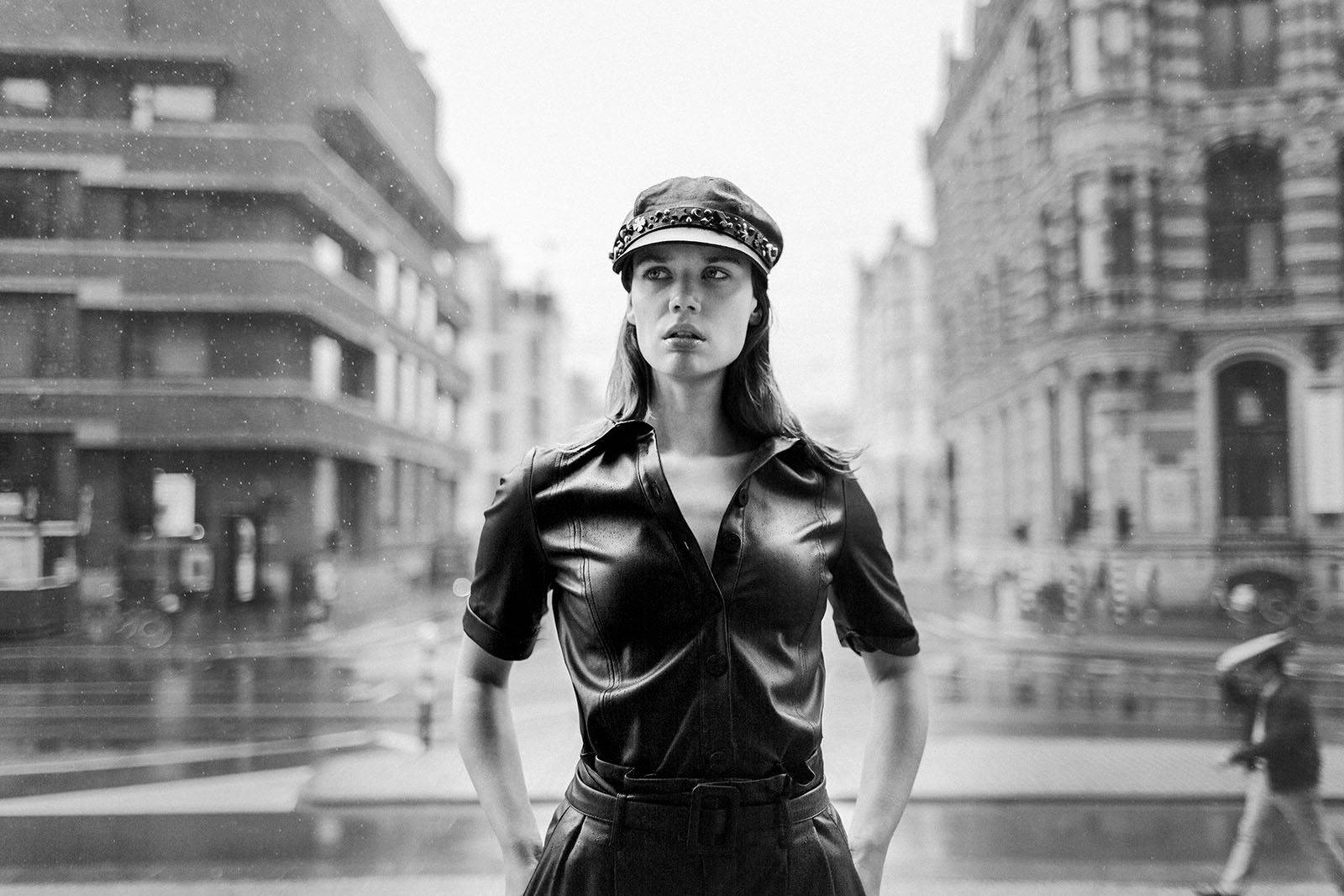 Zwartwit foto van model in zwart leer latex met pet op in Amsterdam bij Magna Plaza achter de Dam