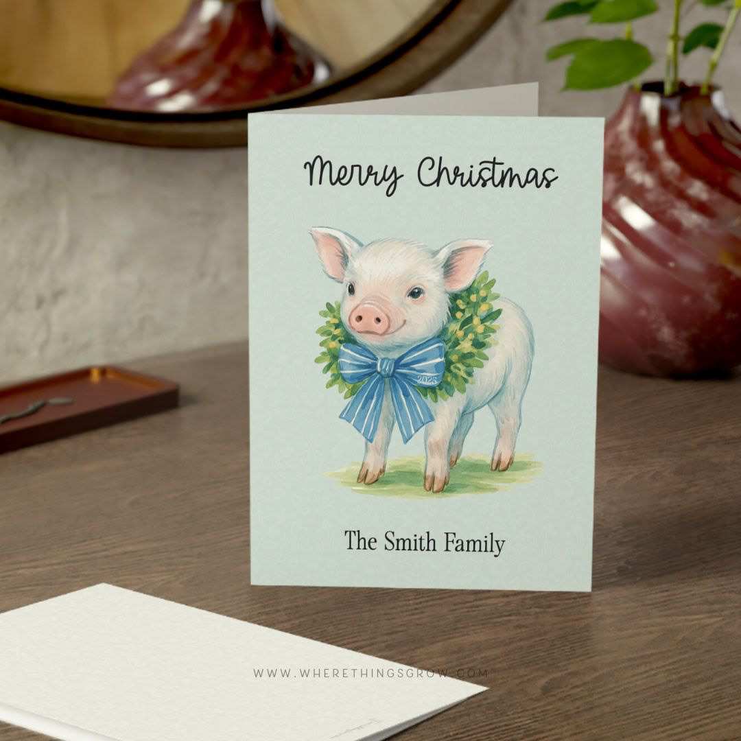 Personalized family Christmas card featuring a baby pig wearing a wreath with a blue bow