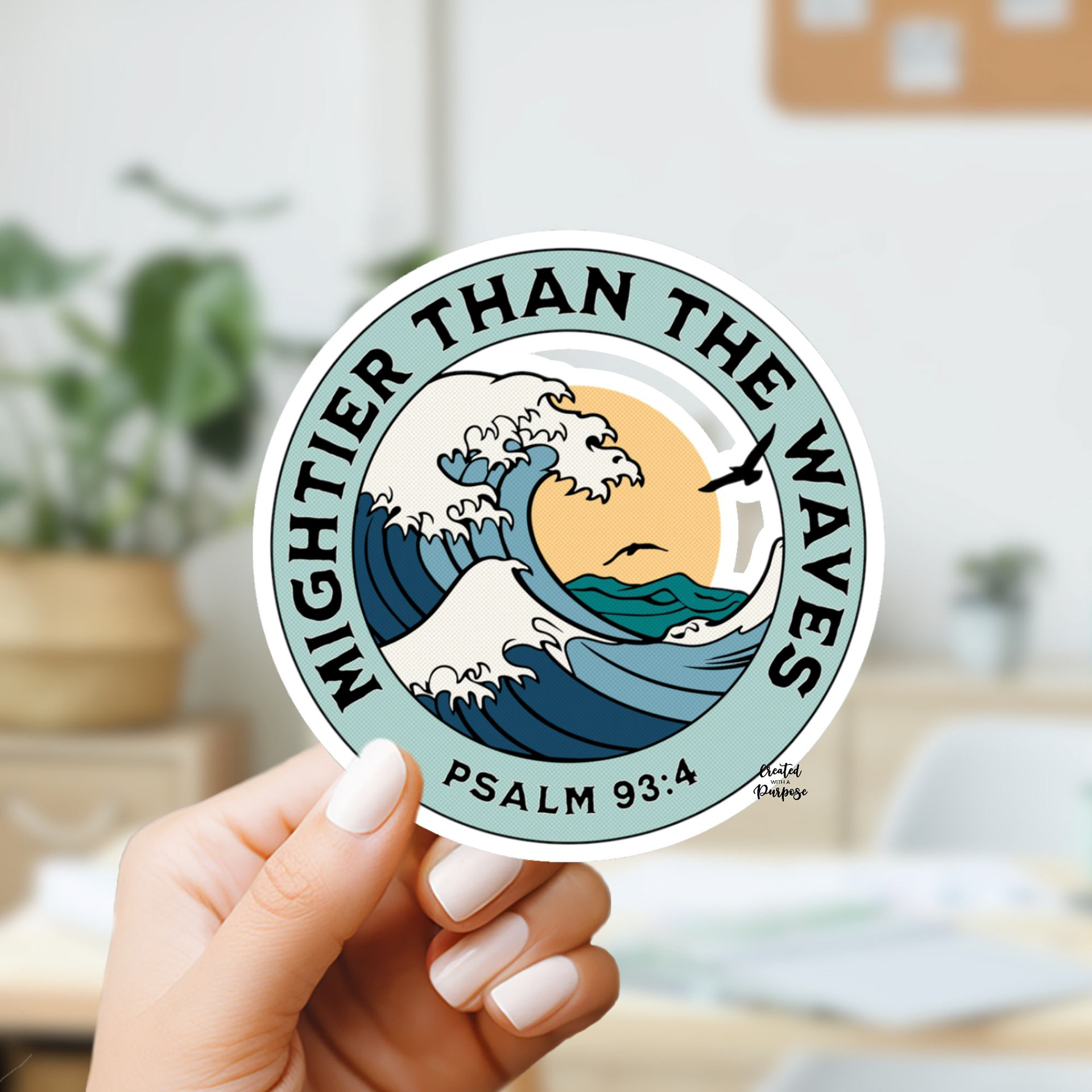 A woman with white nail polish holding a round sticker that says Mightier Than the Waves Psalm 93:4 featuring ocean waves