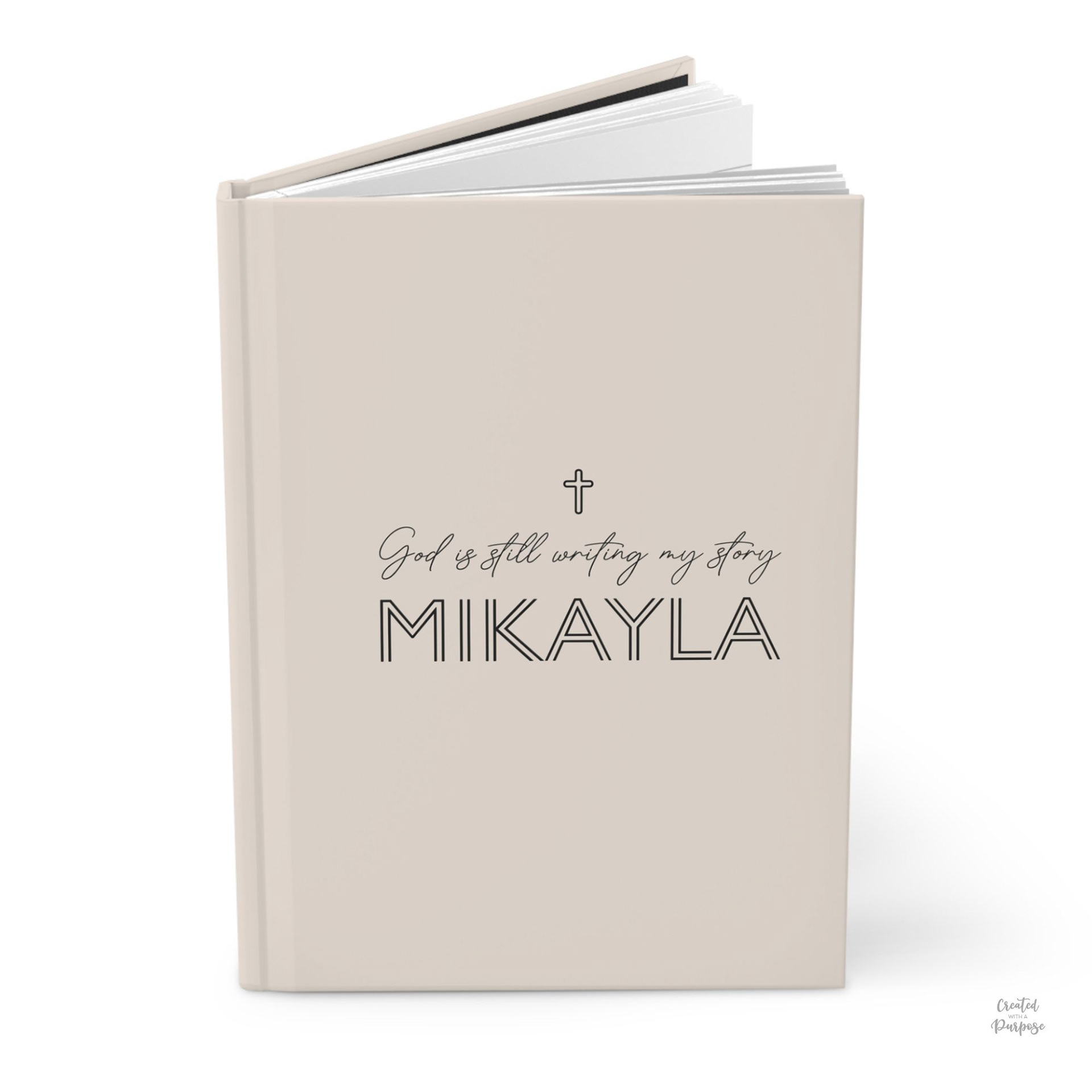Beige Hardcover Journal that says God is still writing my story and a small minimalist cross. Personalized with a first name.