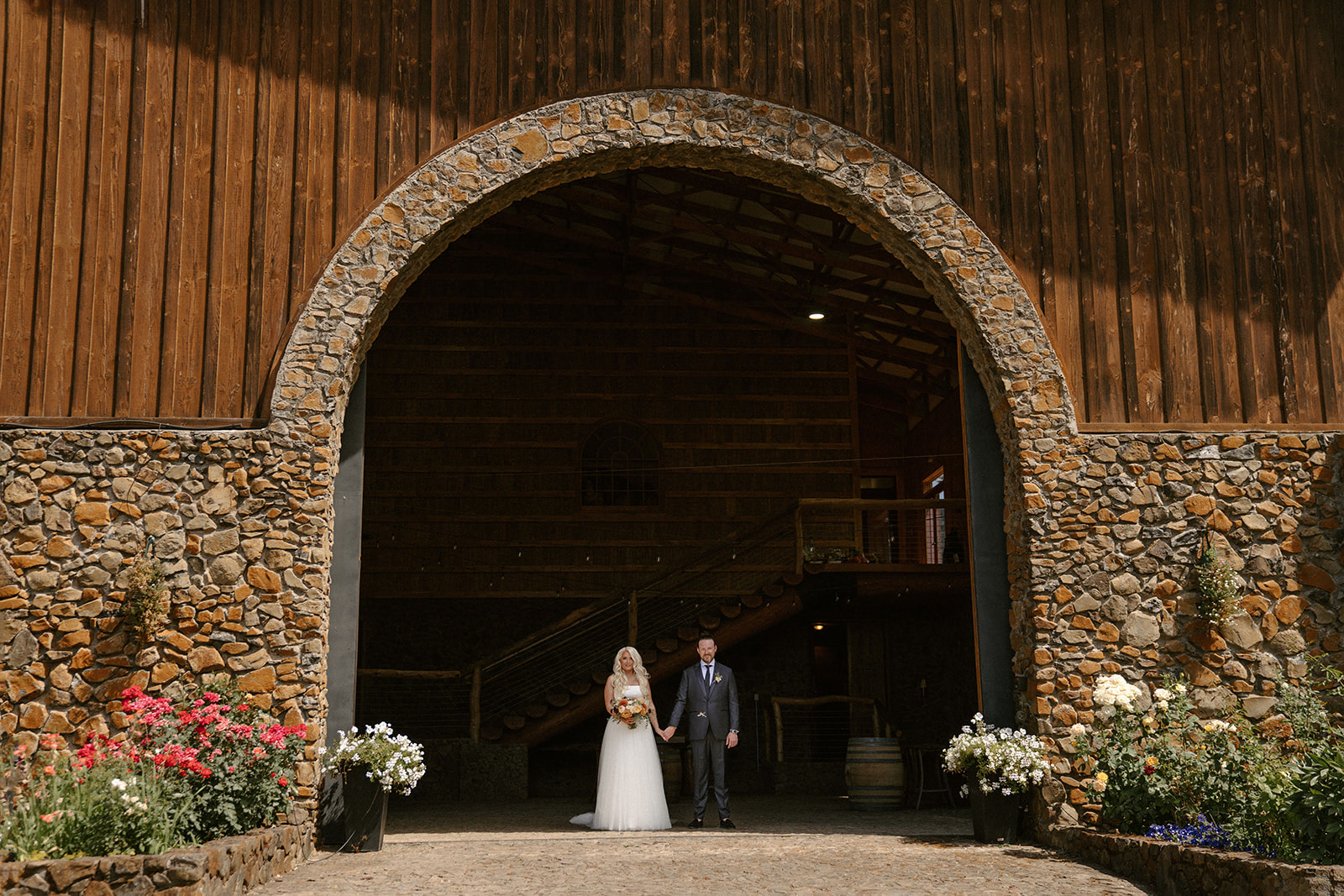 Bride and groom in front of rustic vineyard wedding venue 