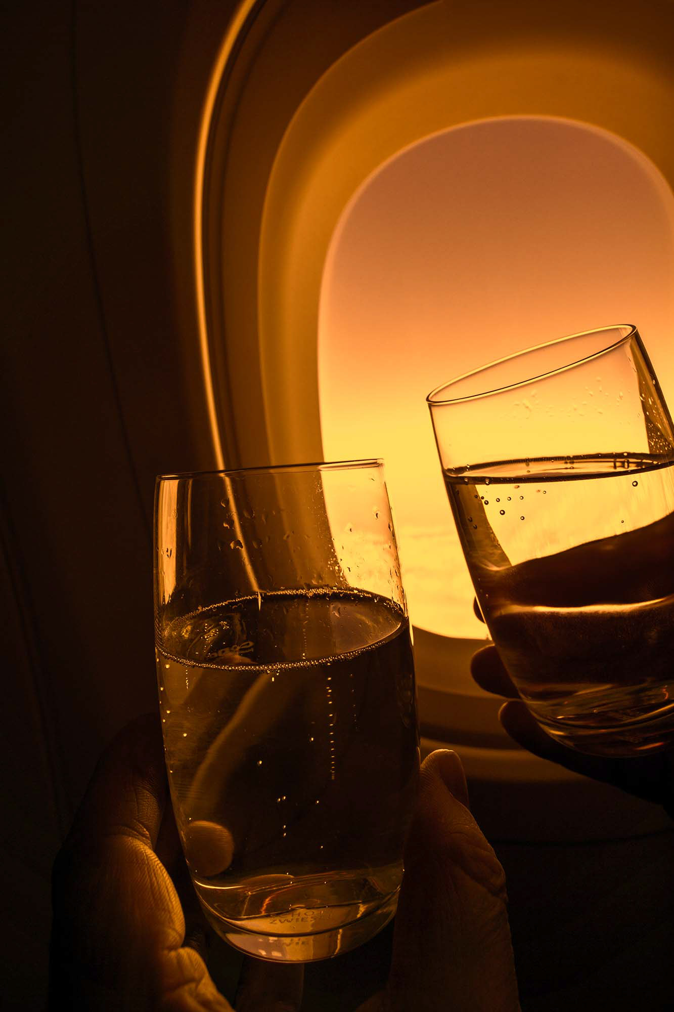 Zwei Gläser mit Sekt beim Anstoßen vor dem Kabinenfenster in einem Flugzeug. Fotograf Klaus Ohlenschläger - Frankfurt - Bad Homburg – Kronberg
