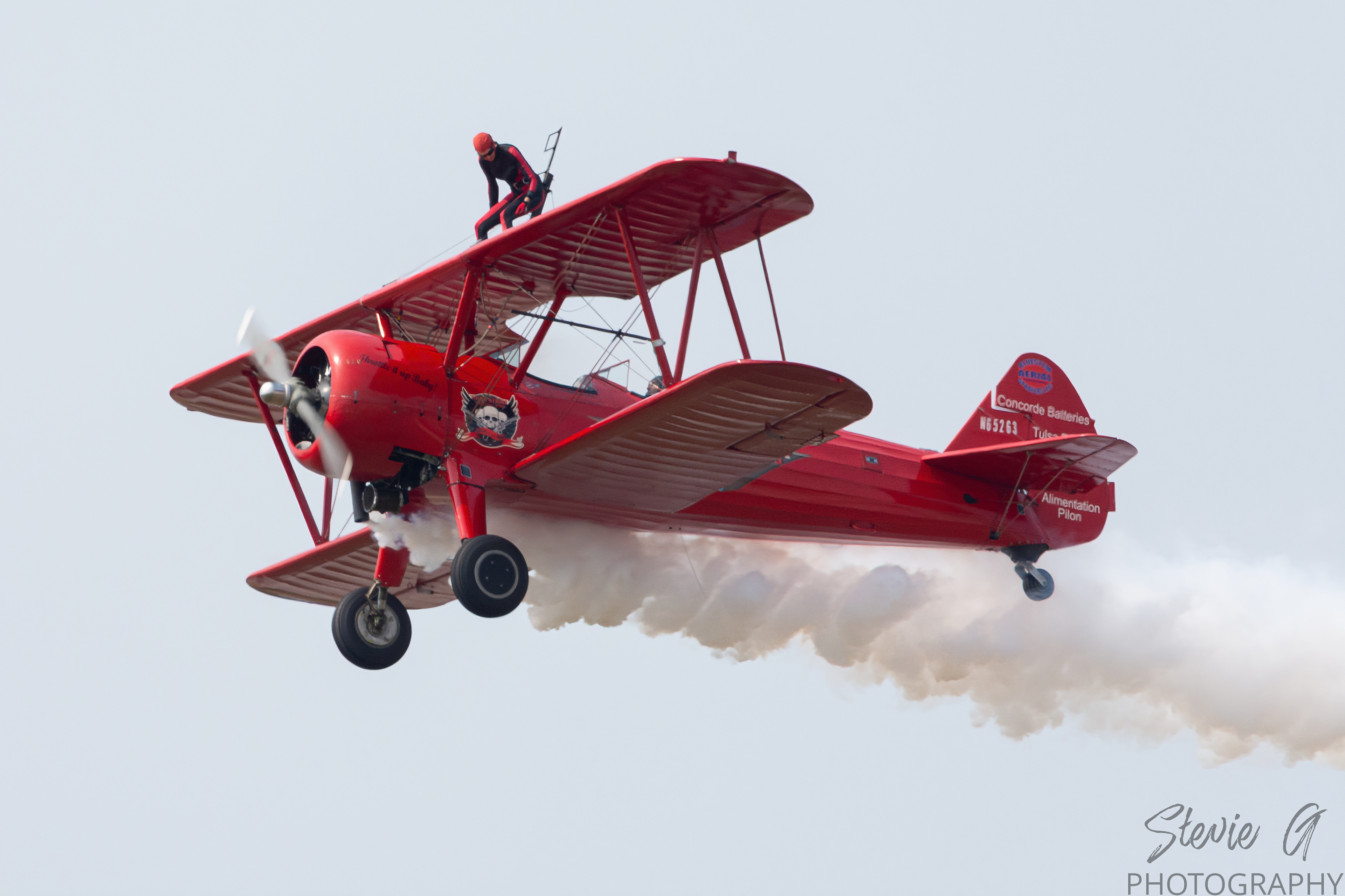 Stunt atop a red 1940 Boeing-Stearman biplane during an airshow display. 