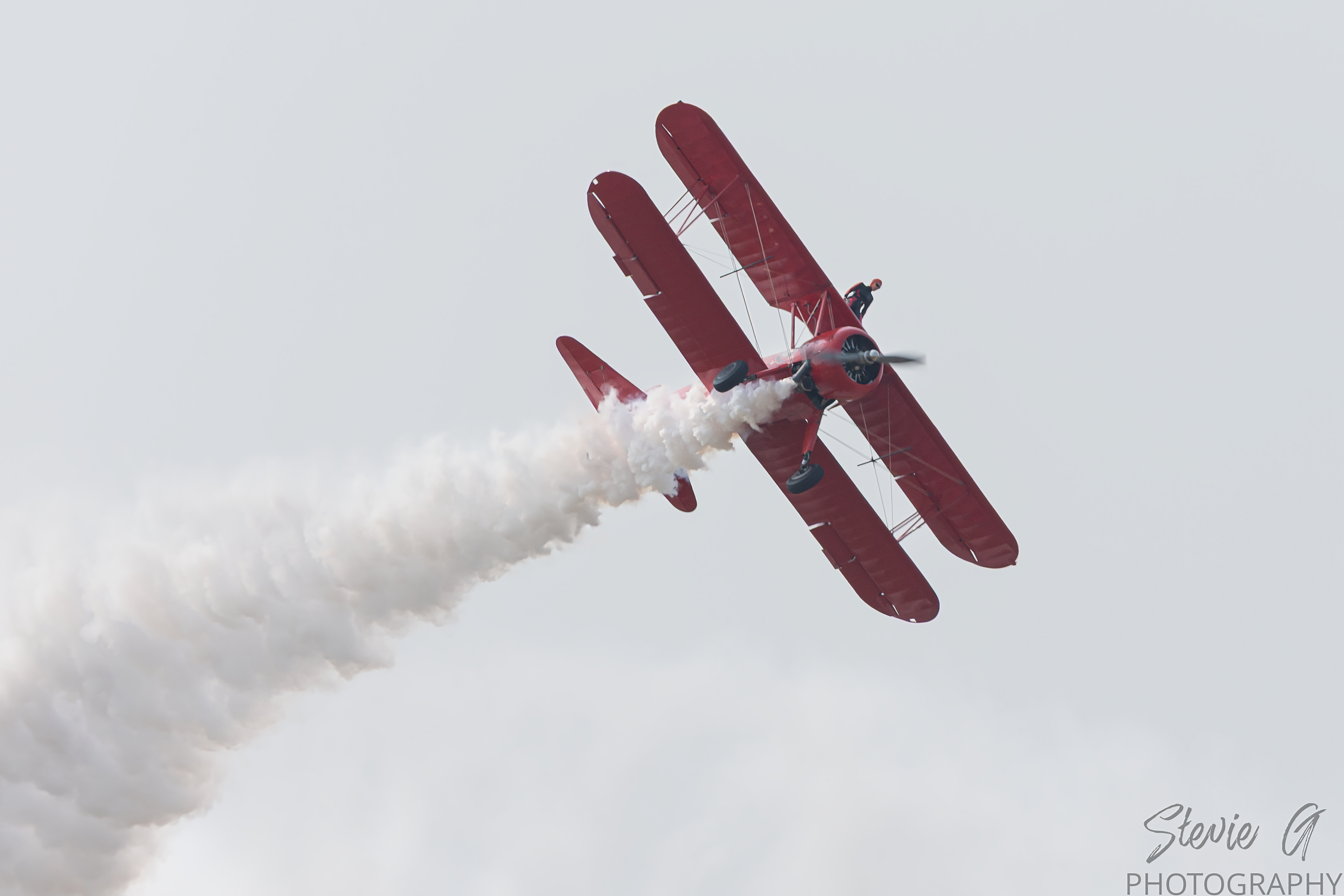 Stunt atop a red 1940 Boeing-Stearman biplane during an airshow display. 