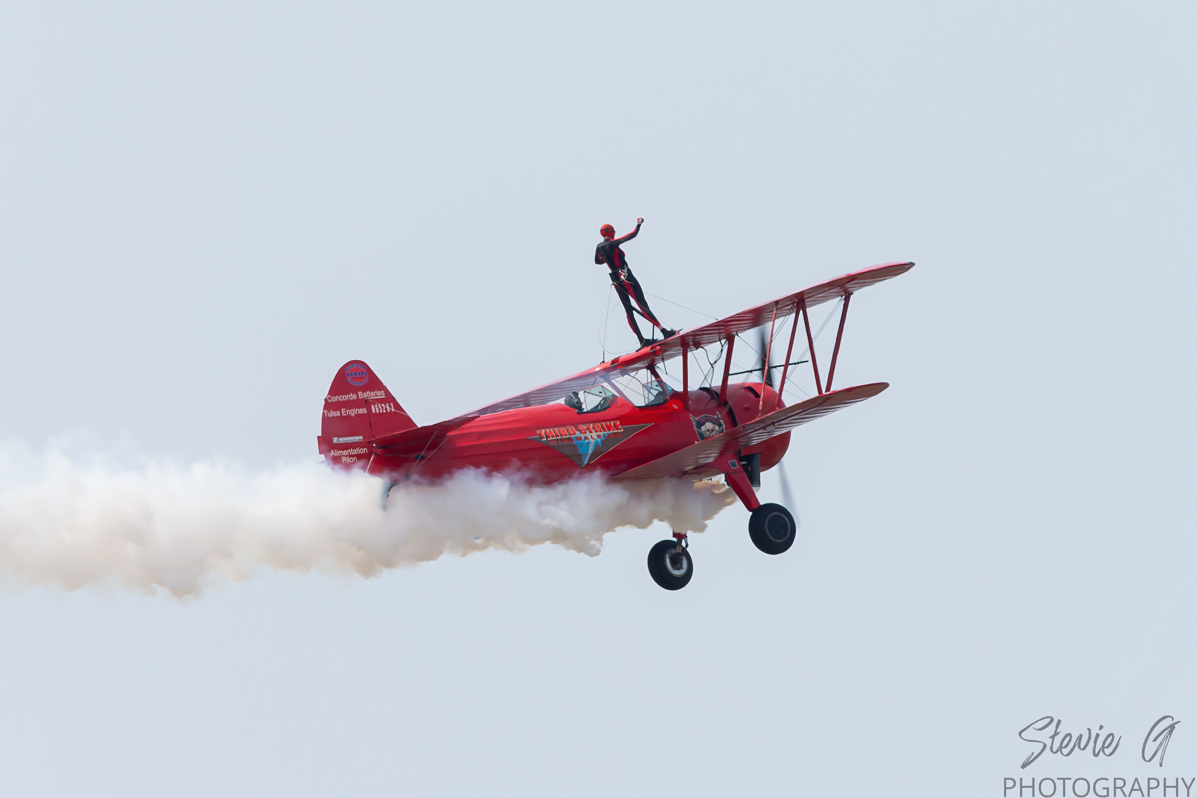 Stunt atop a red 1940 Boeing-Stearman biplane during an airshow display. 