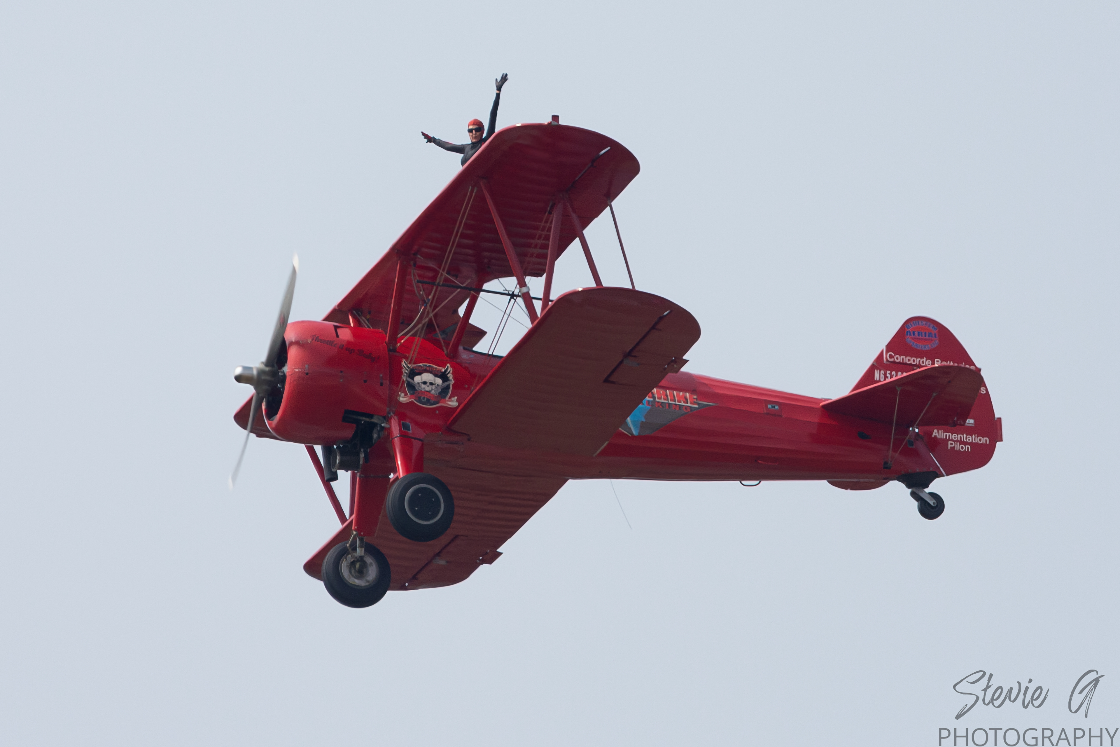 Stunt atop a red 1940 Boeing-Stearman biplane during an airshow display. 