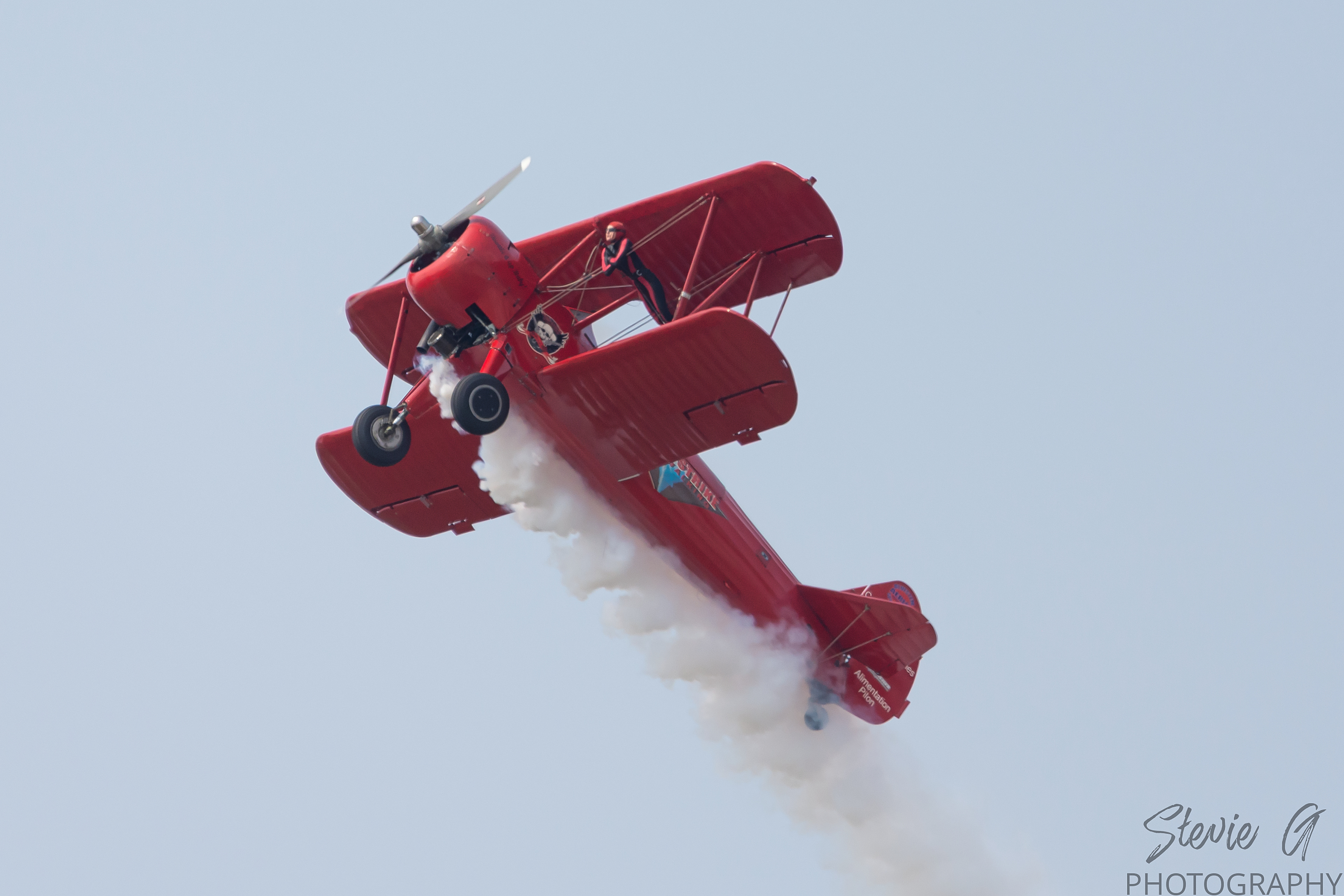 Stunt atop a red 1940 Boeing-Stearman biplane during an airshow display. 