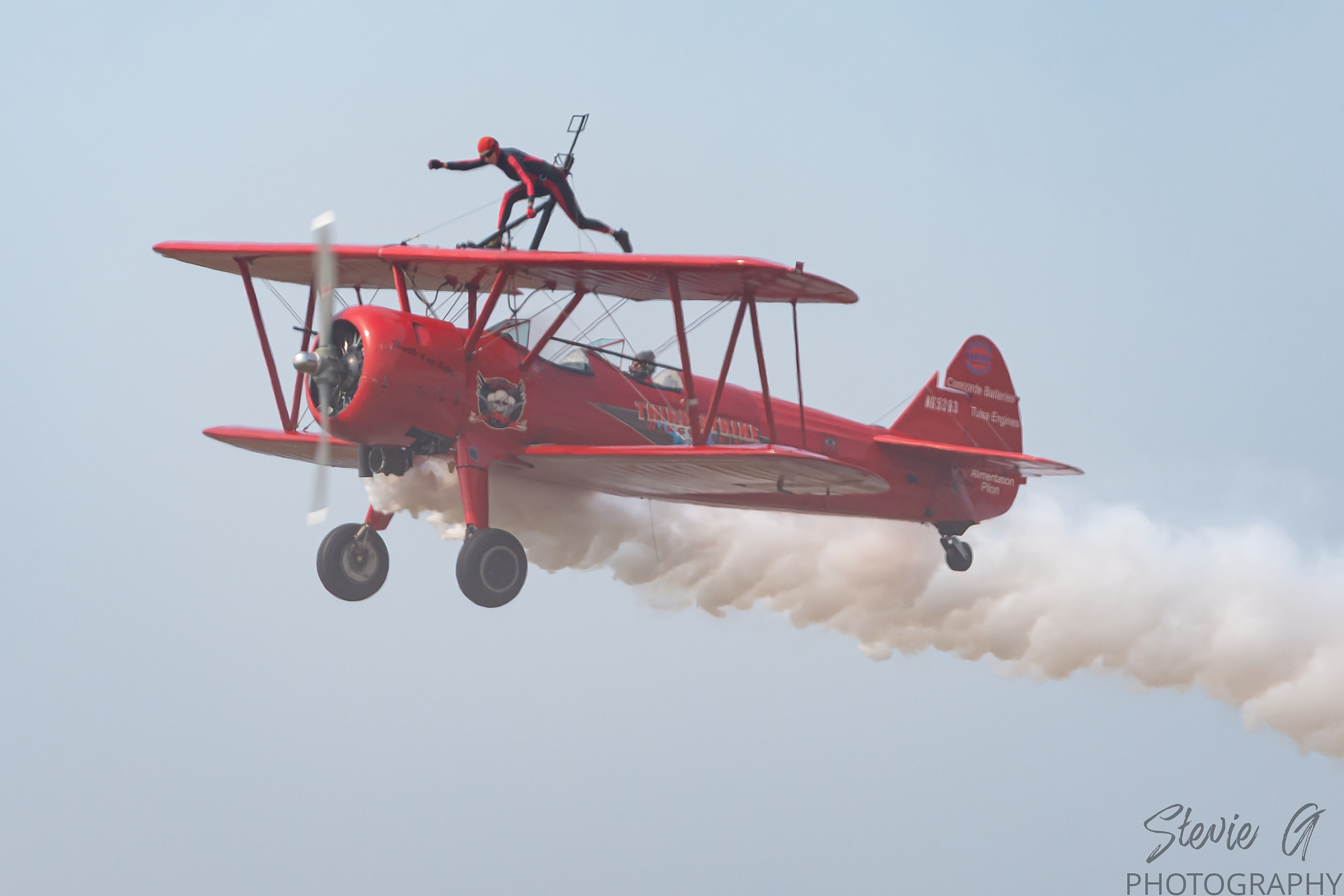 Stunt atop a red 1940 Boeing-Stearman biplane during an airshow display. 