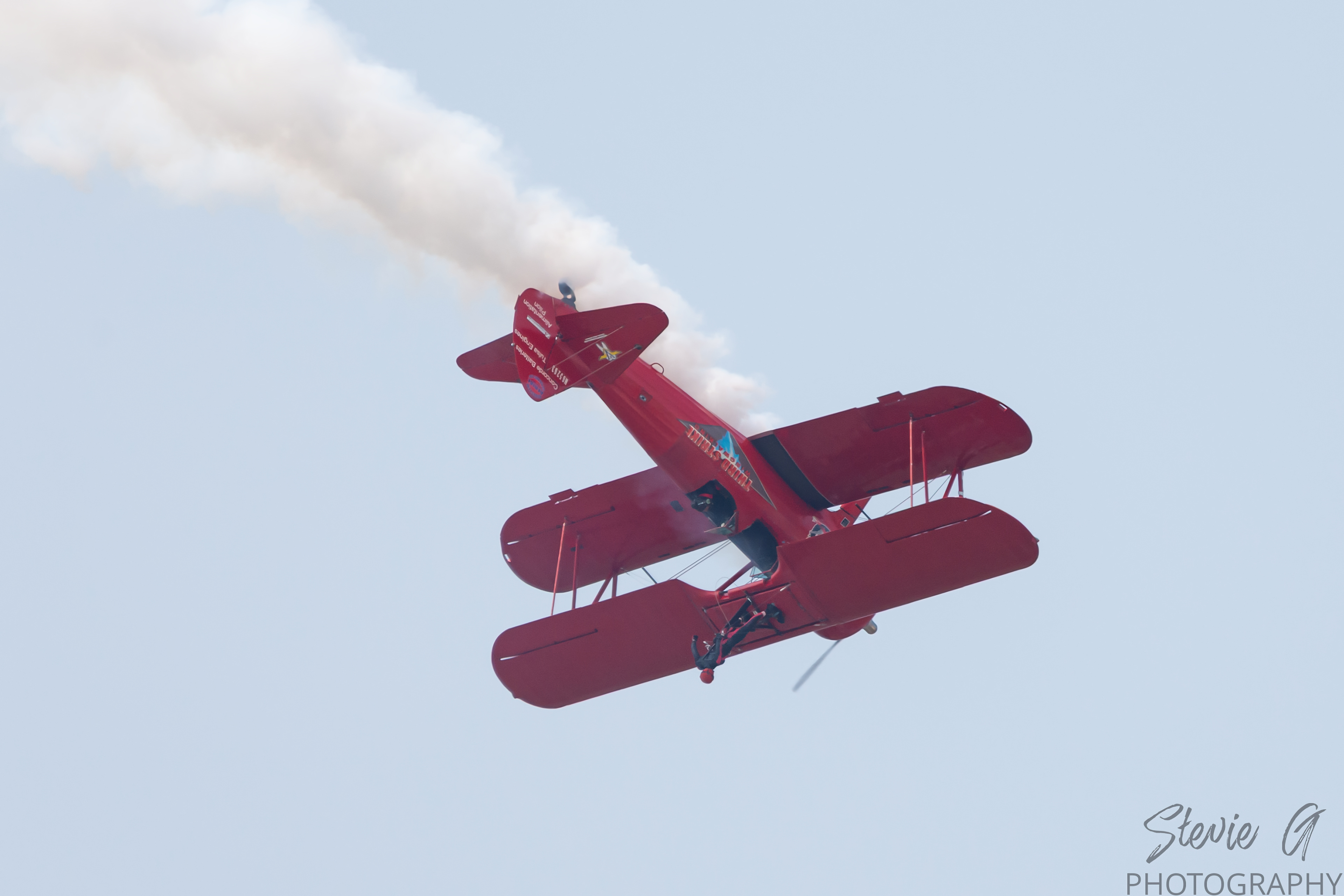 Stunt atop a red 1940 Boeing-Stearman biplane during an airshow display. 
