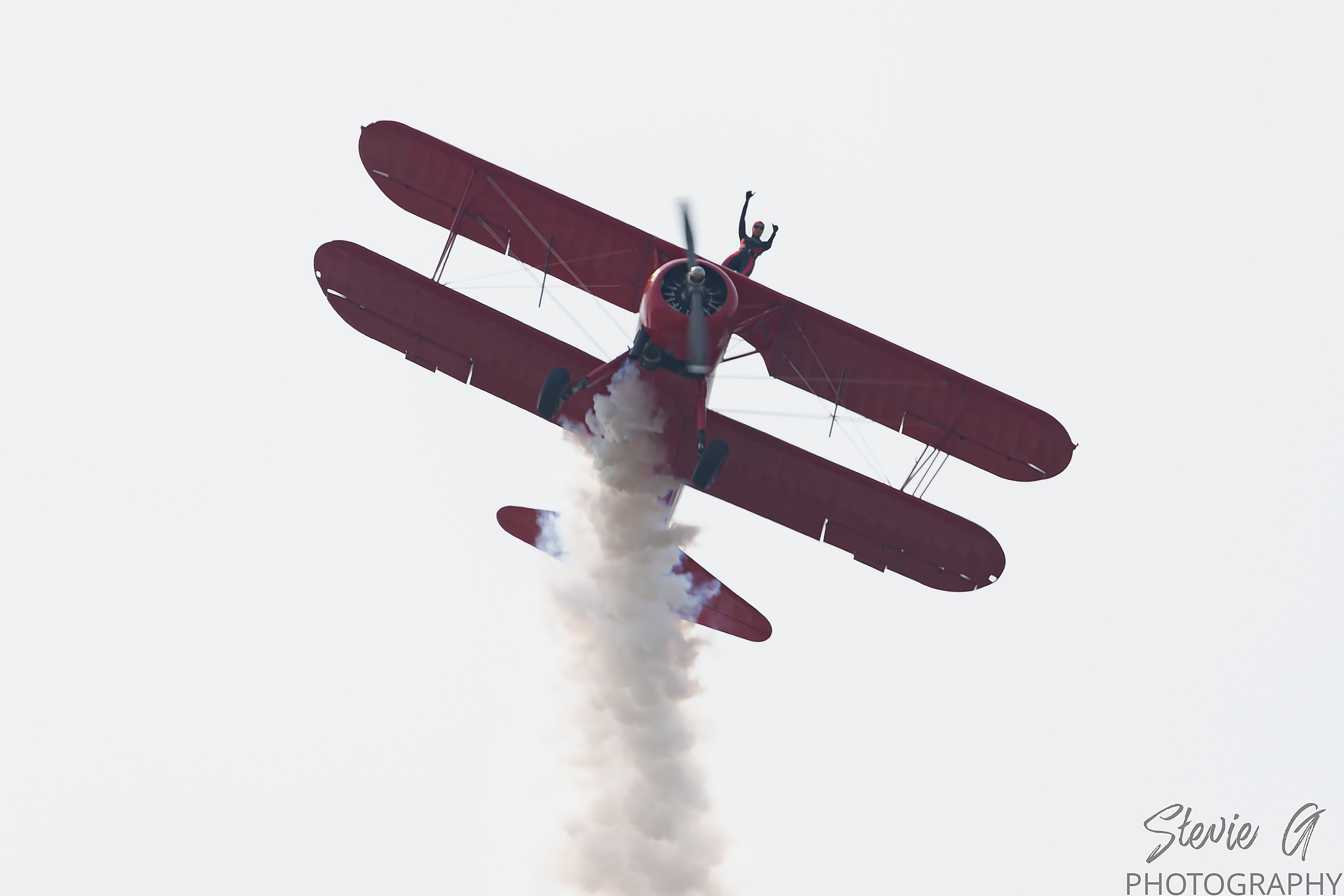 Stunt atop a red 1940 Boeing-Stearman biplane during an airshow display. 
