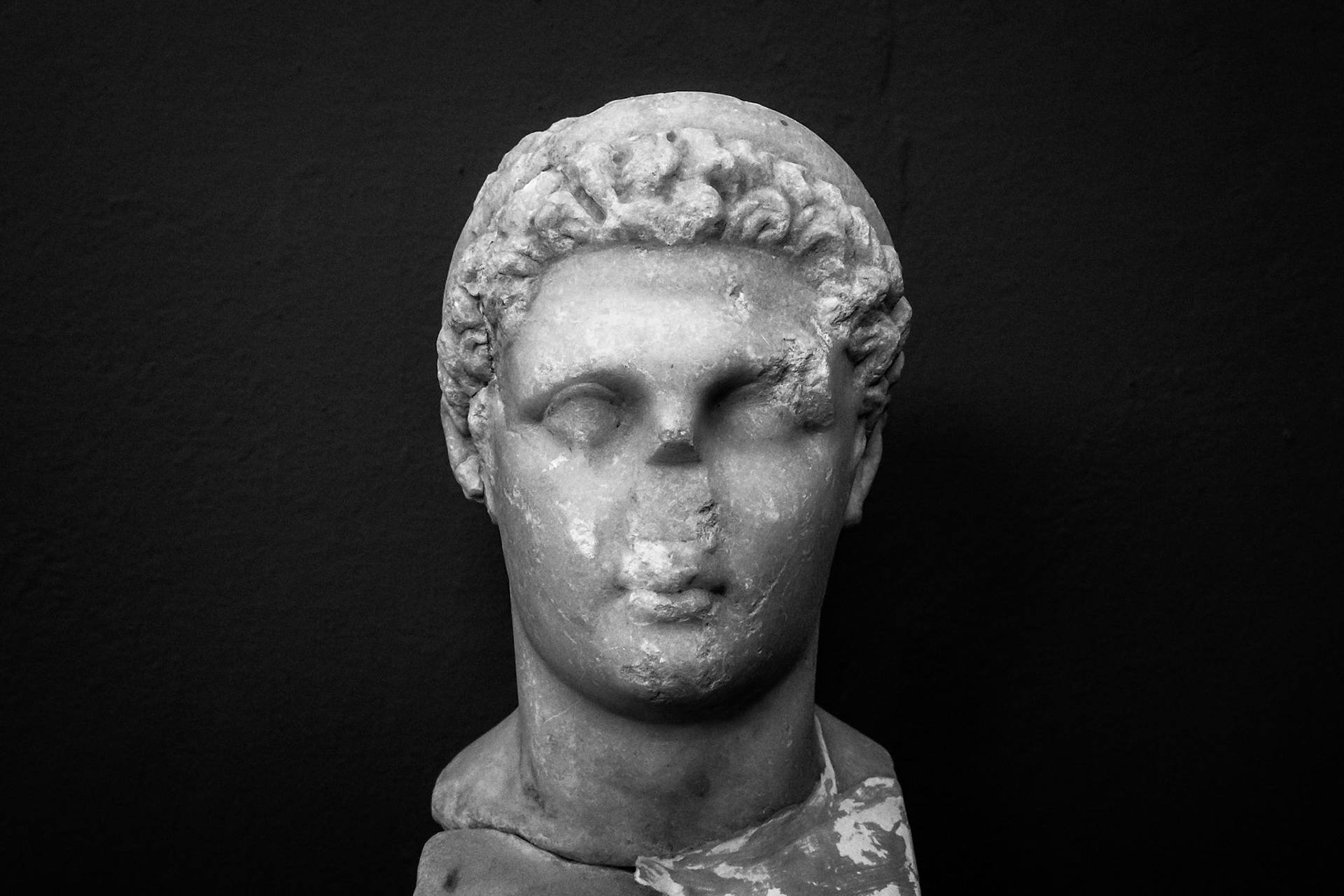 Delos, Greece - May 22nd 2018: A marble bust of a young man with curly hair, likely a depiction of a deity or important figure, stands as a testament to ancient Greek artistry.