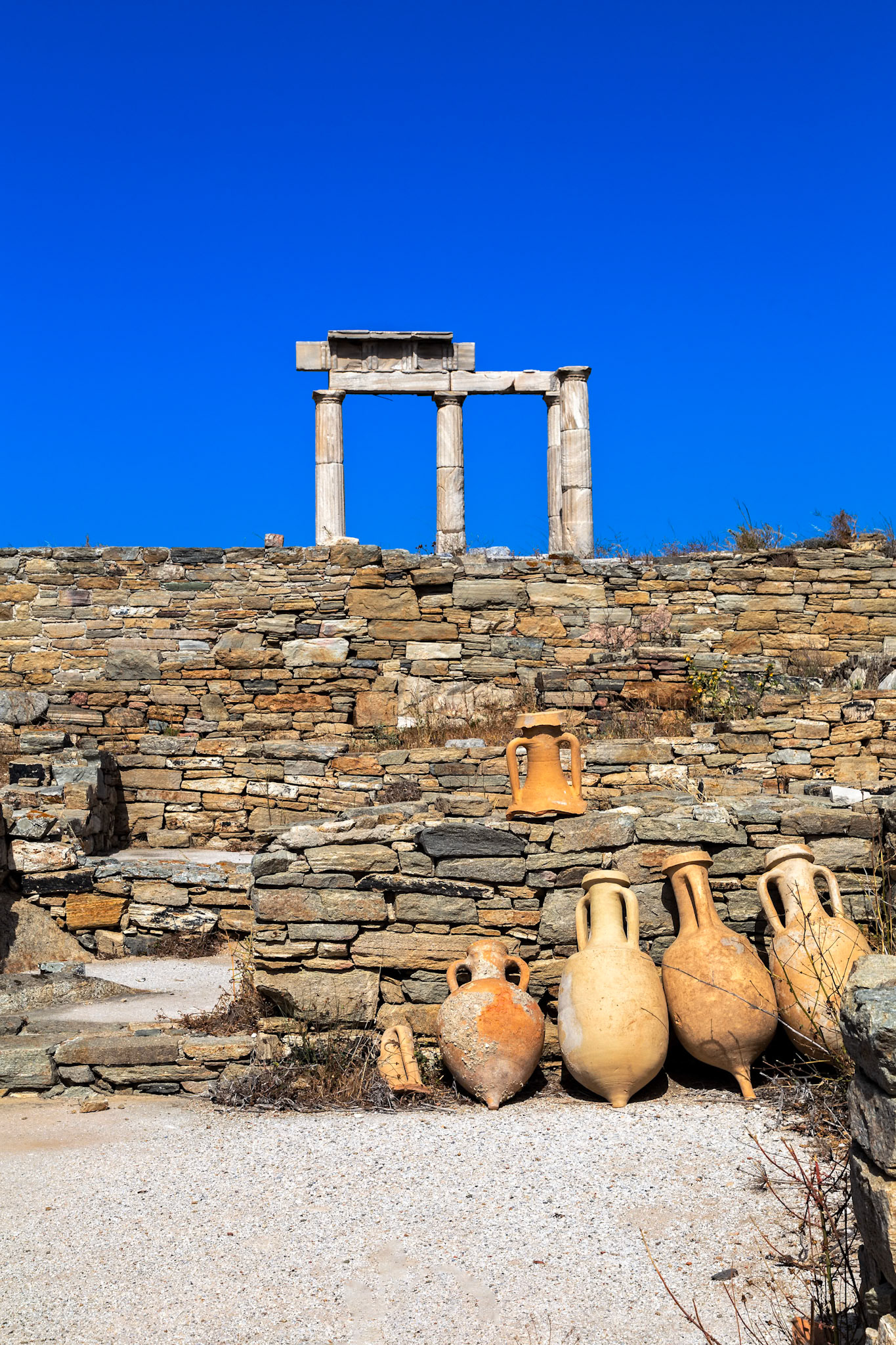 Delos, Greece - May 22nd 2018: Ancient Greek ruins are preserved on the island of Delos, including amphorae and the Temple of Isis, for historical and cultural appreciation.